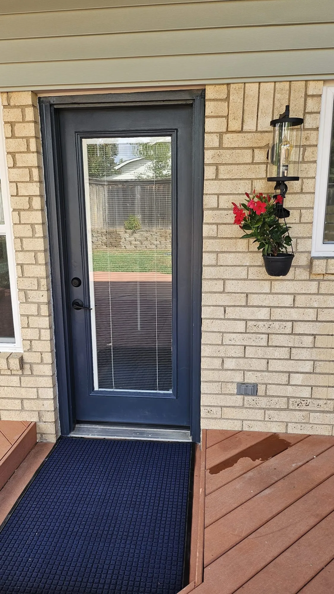 Dark-paneled exterior door with a glass insert, set within a light brick facade