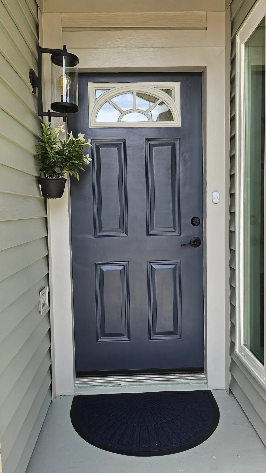Panel-style entry door with an arched transom window, finished in a deep blue-gray hue