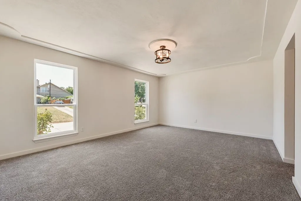 Spacious interior room featuring plush gray carpeting and neutral wall tones