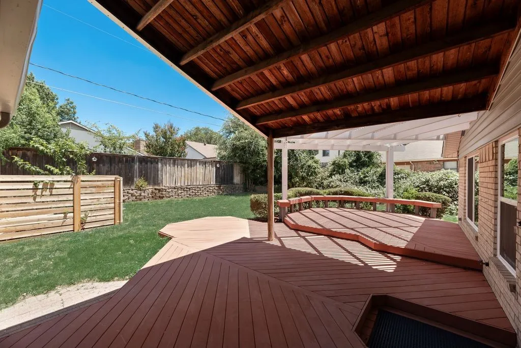Expansive multi-level wood-finish deck featuring a built-in bench seating area and partial overhead coverage