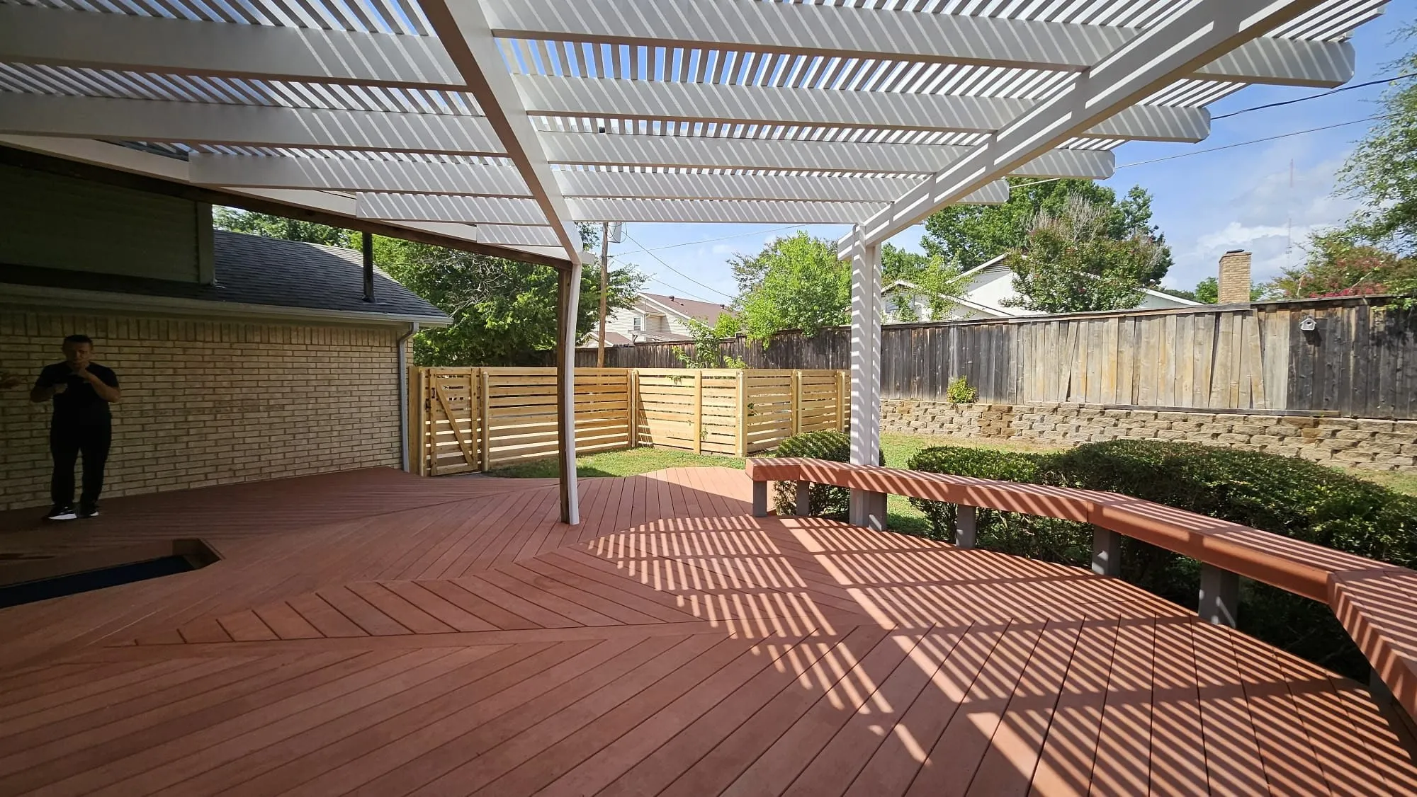 Expansive wood-finish deck with a white slatted pergola