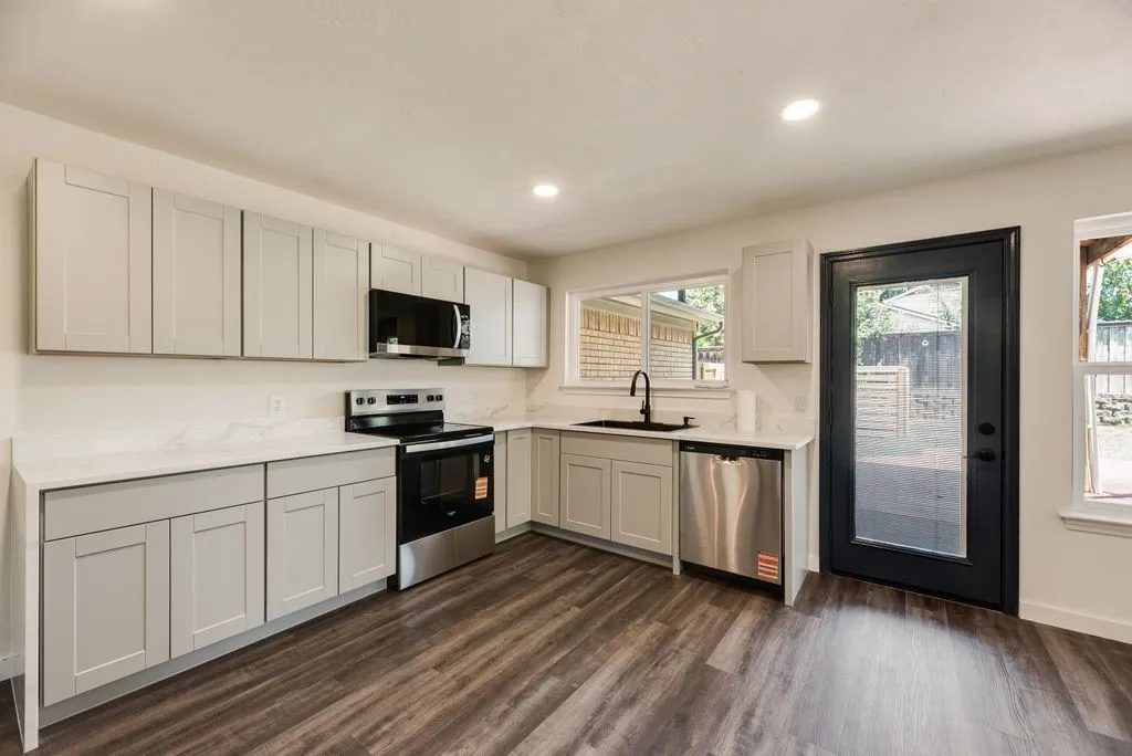Contemporary kitchen featuring light gray shaker-style cabinetry, white countertops, stainless steel appliances, wood-finish flooring, and recessed lighting