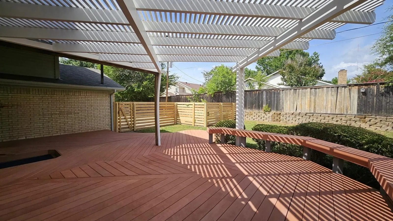 Expansive outdoor decking with a contemporary pergola featuring slatted roofing and integrated bench seating