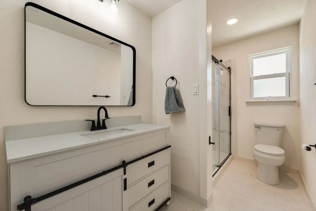 Bathroom featuring a white vanity with a barn door-style cabinet, a rectangular undermount sink, and a black faucet