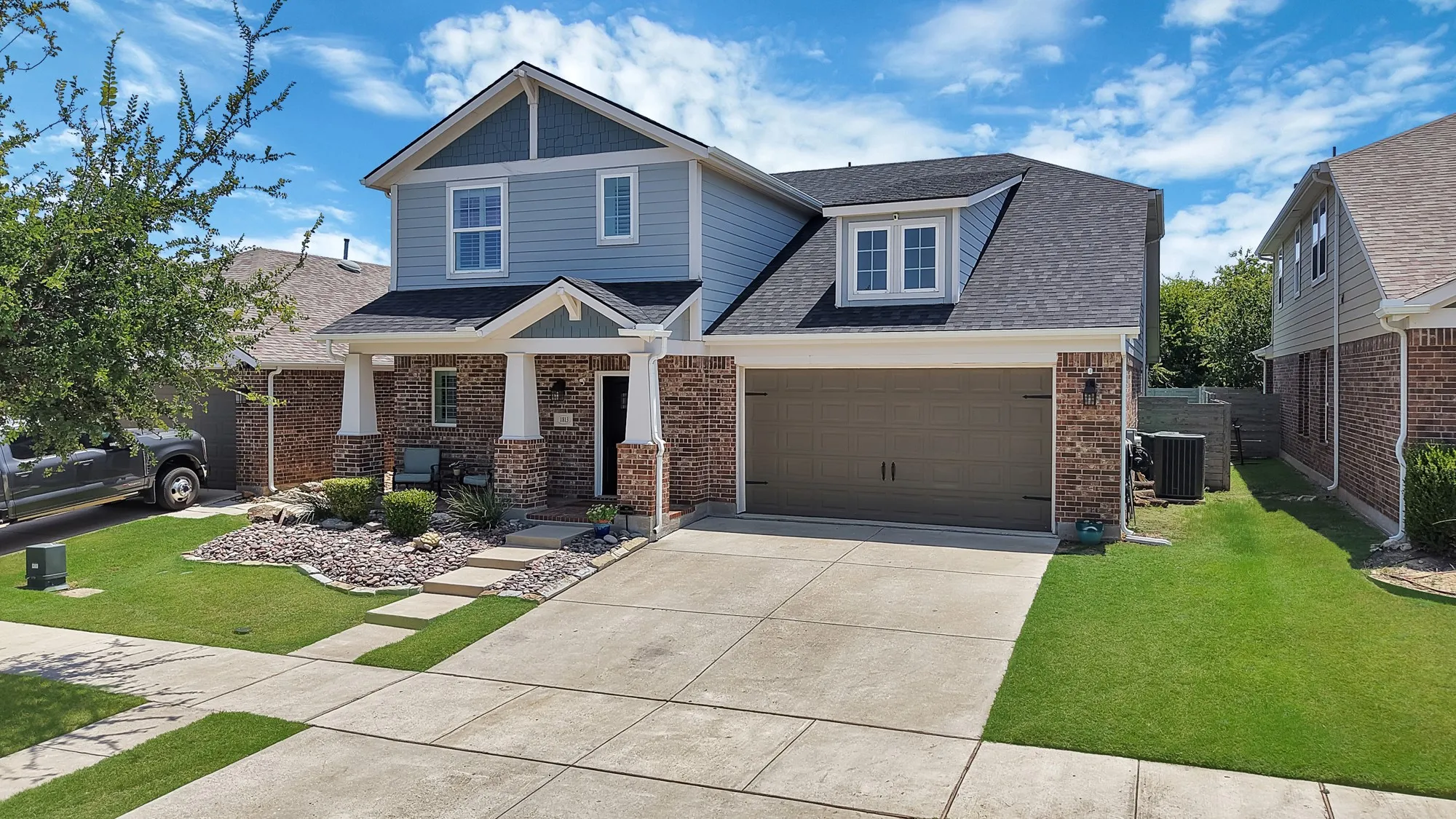 Two-story residence featuring brick and siding exterior, a two-car garage, and a covered front porch with columns