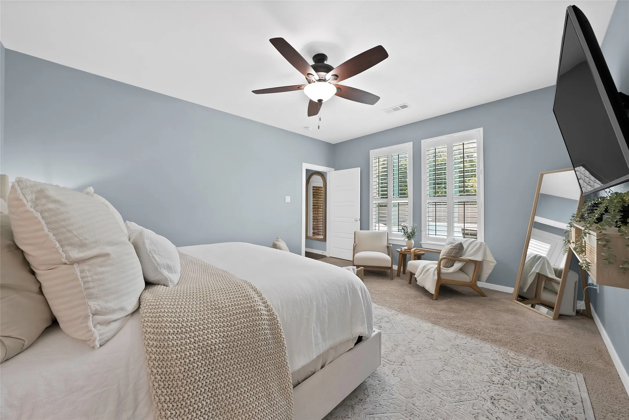 Spacious bedroom featuring light blue walls and neutral carpet flooring
