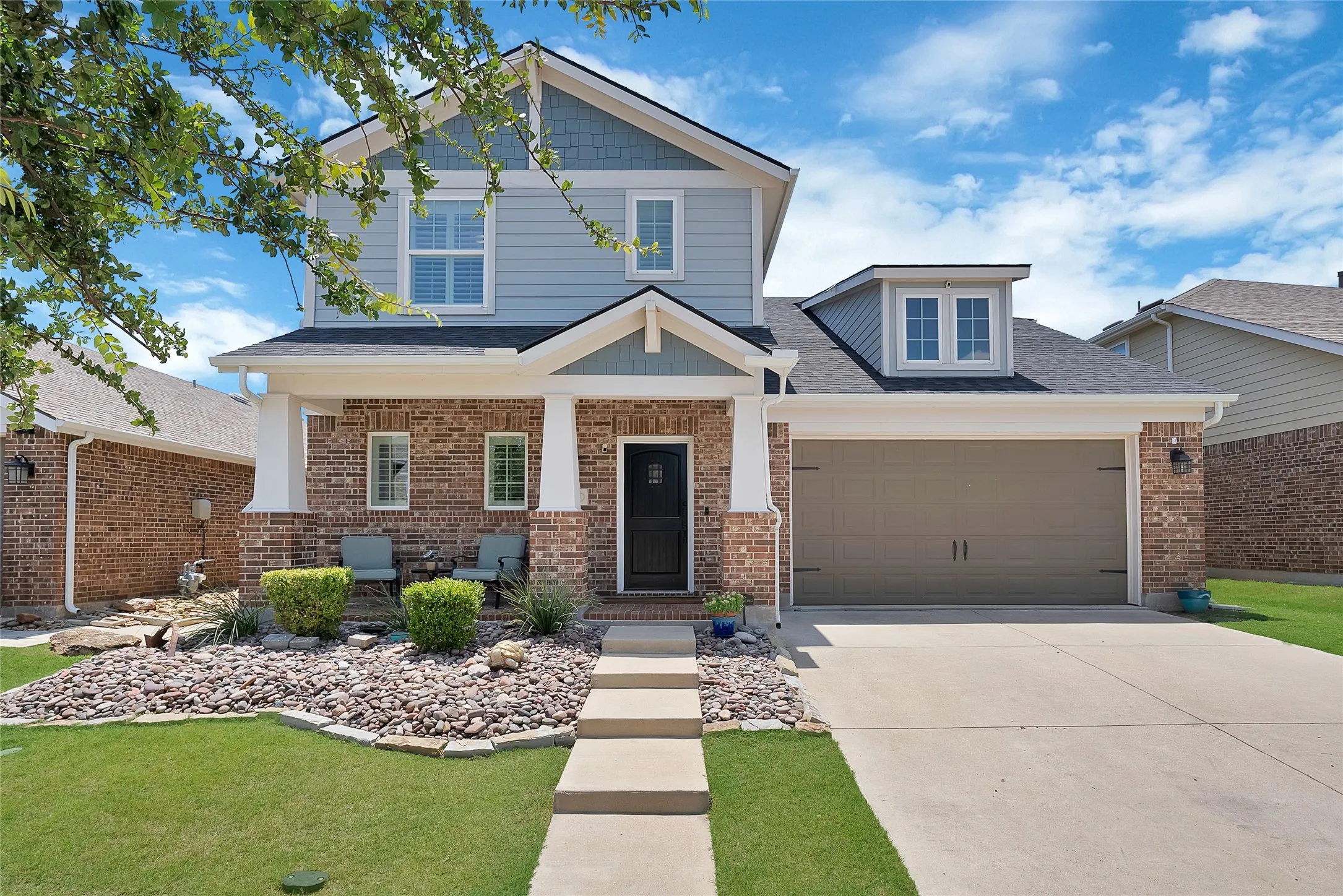 Two-story residence featuring a brick and siding exterior, covered front porch, and an attached two-car garage