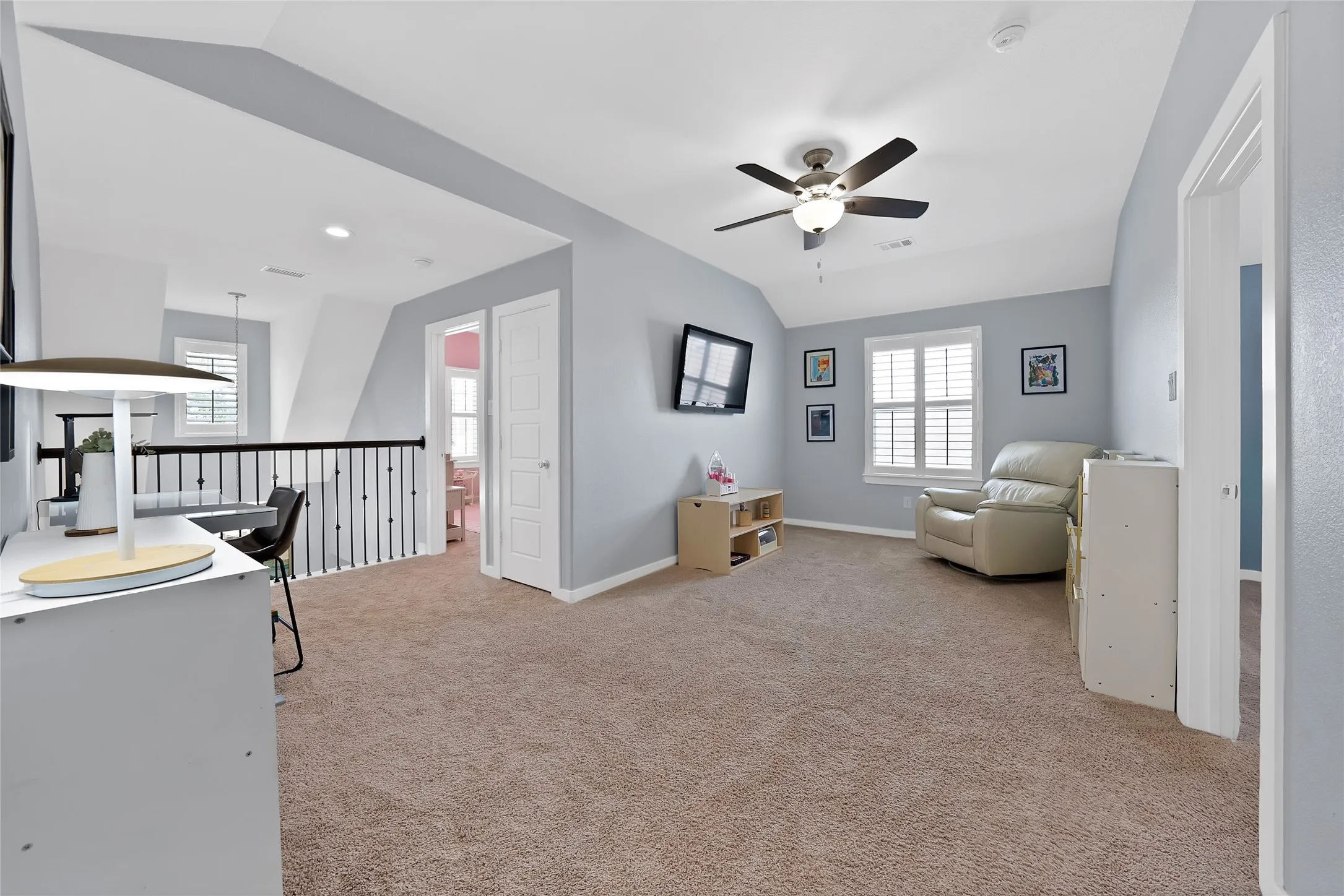 Spacious upper-level loft featuring vaulted ceilings, a ceiling fan with integrated lighting, and carpeted flooring