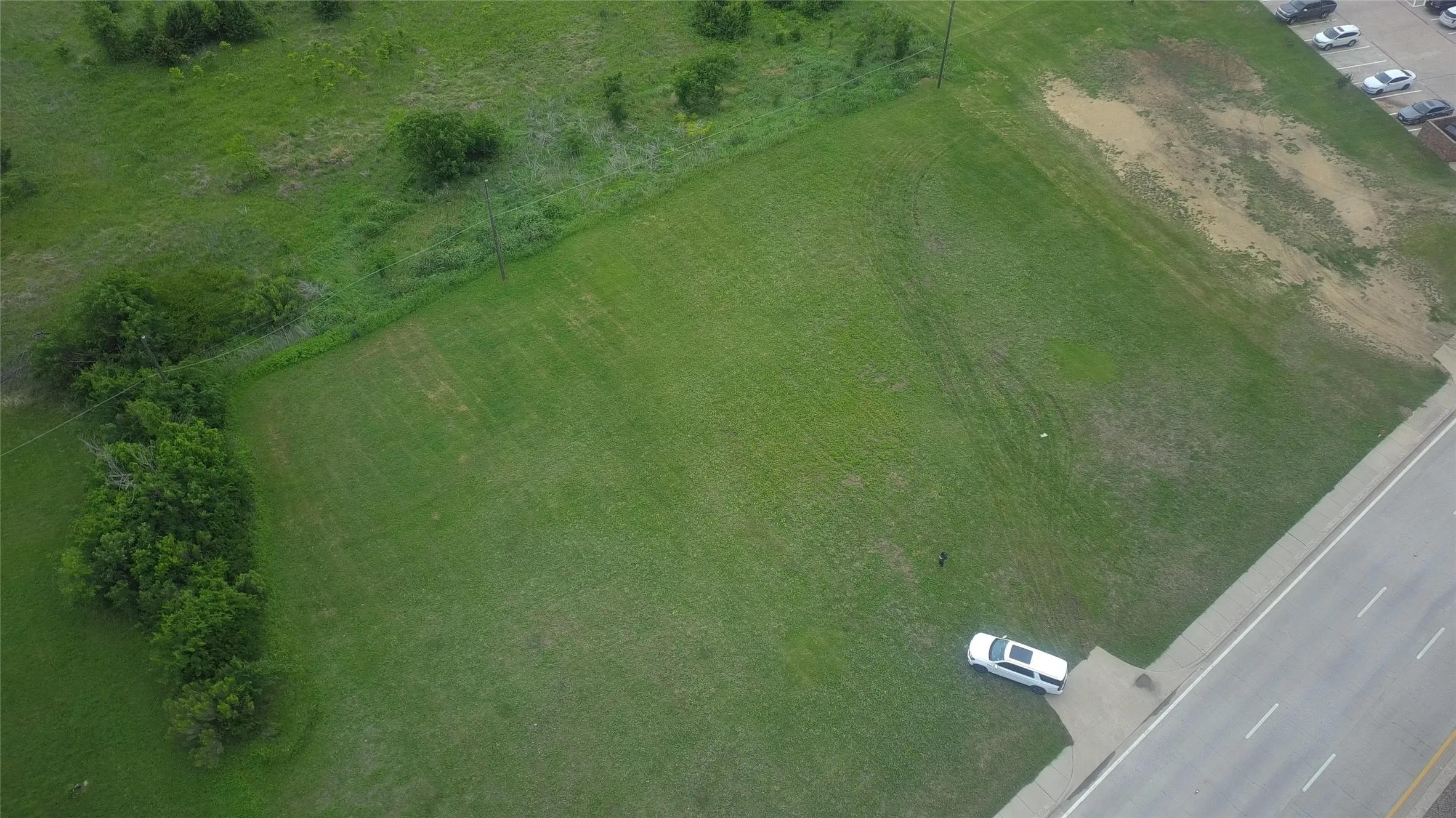 Expansive green space with perimeter tree line and road frontage