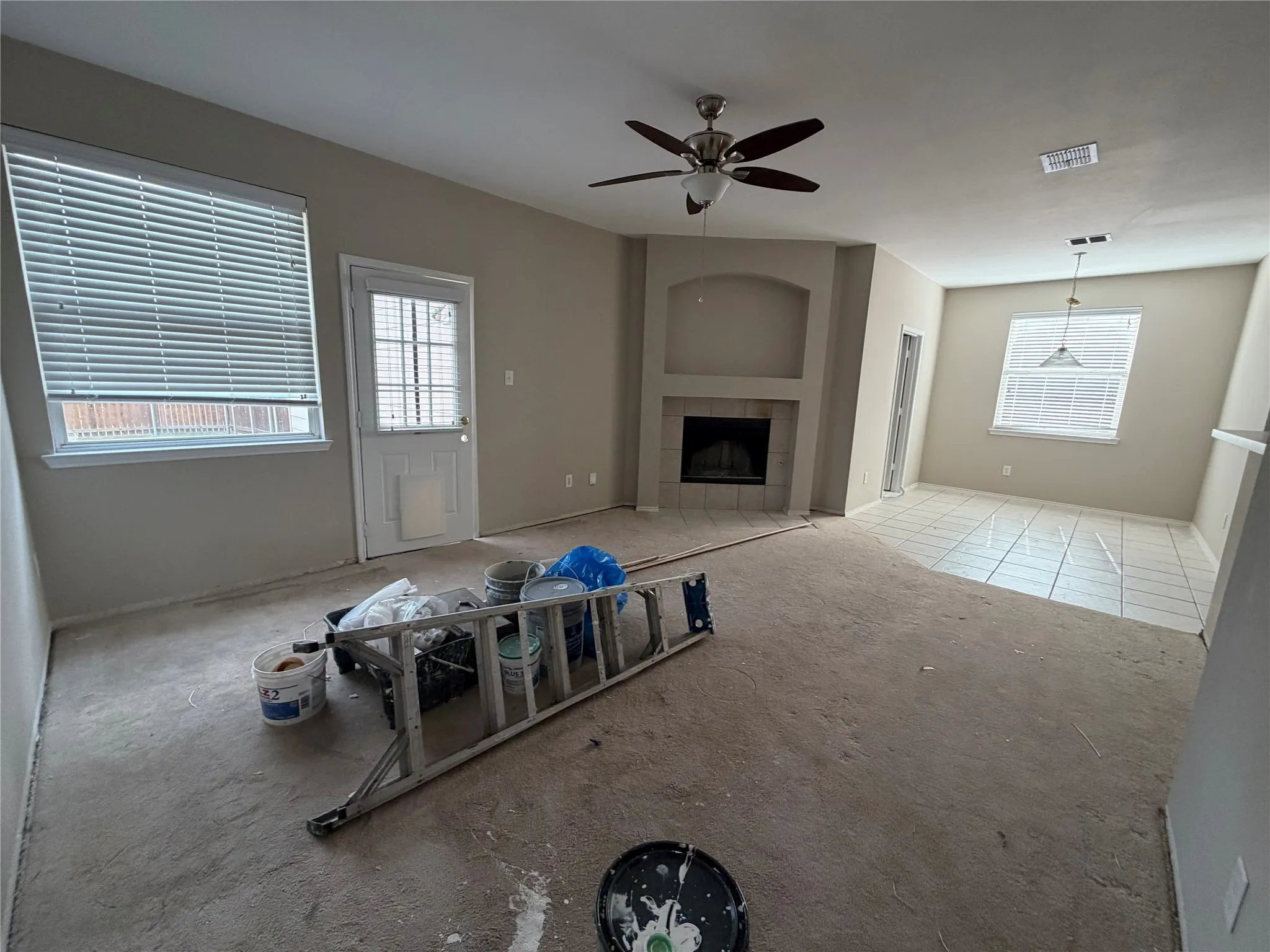 Corner fireplace with a mantel, ceiling fan, white window blinds, and white panel door