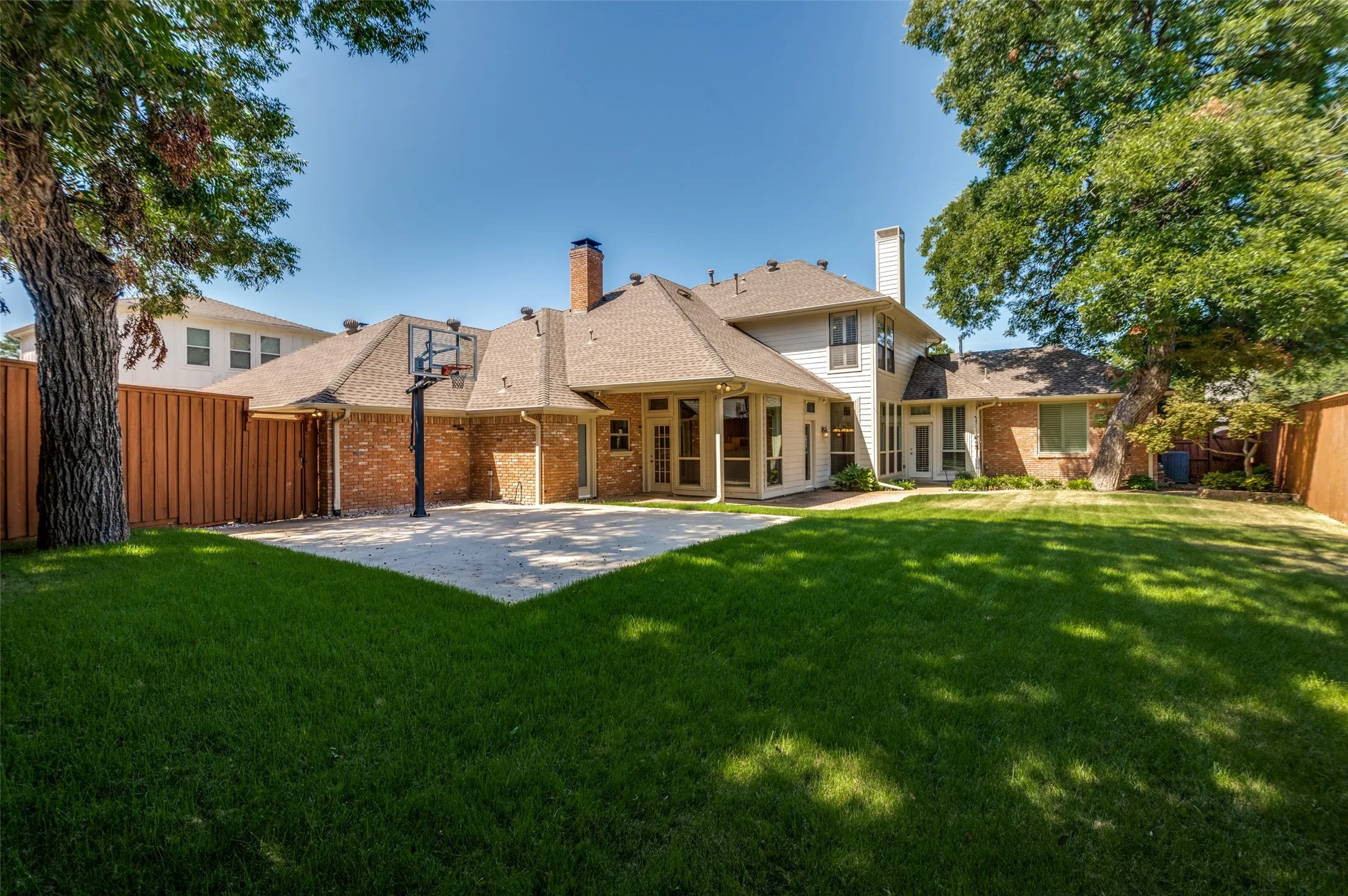 Lots of grassy space, plus trees, plus covered patio, plus privacy fence, plus sport court!