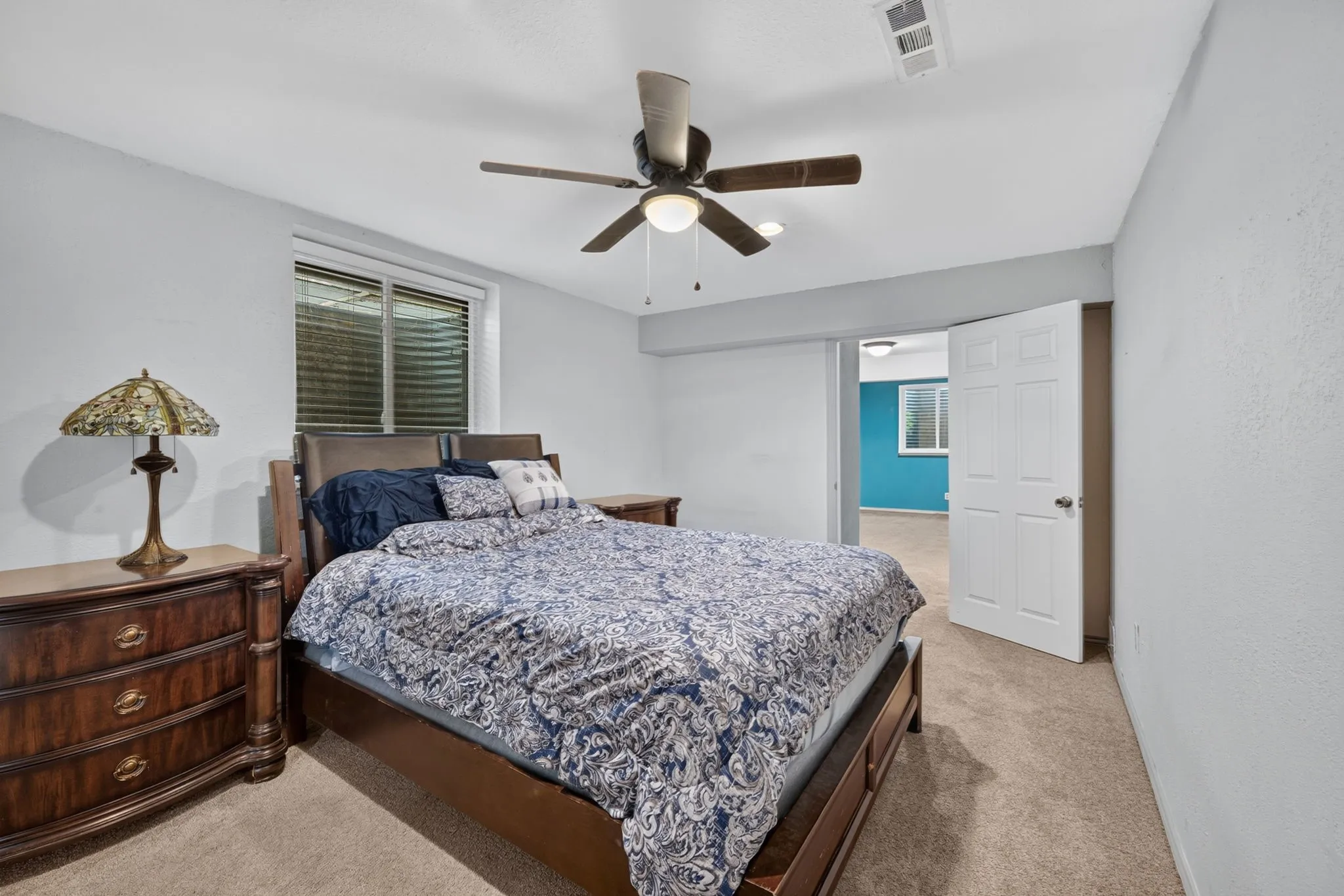 Carpeted bedroom featuring a ceiling fan, white trim, and a window with blinds