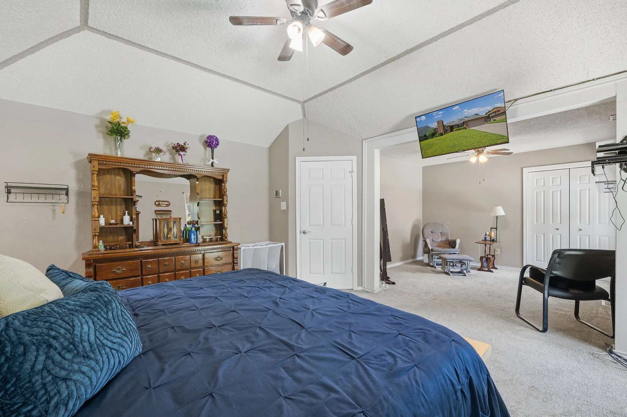 Spacious bedroom with vaulted ceilings, neutral-toned walls, and ceiling fan