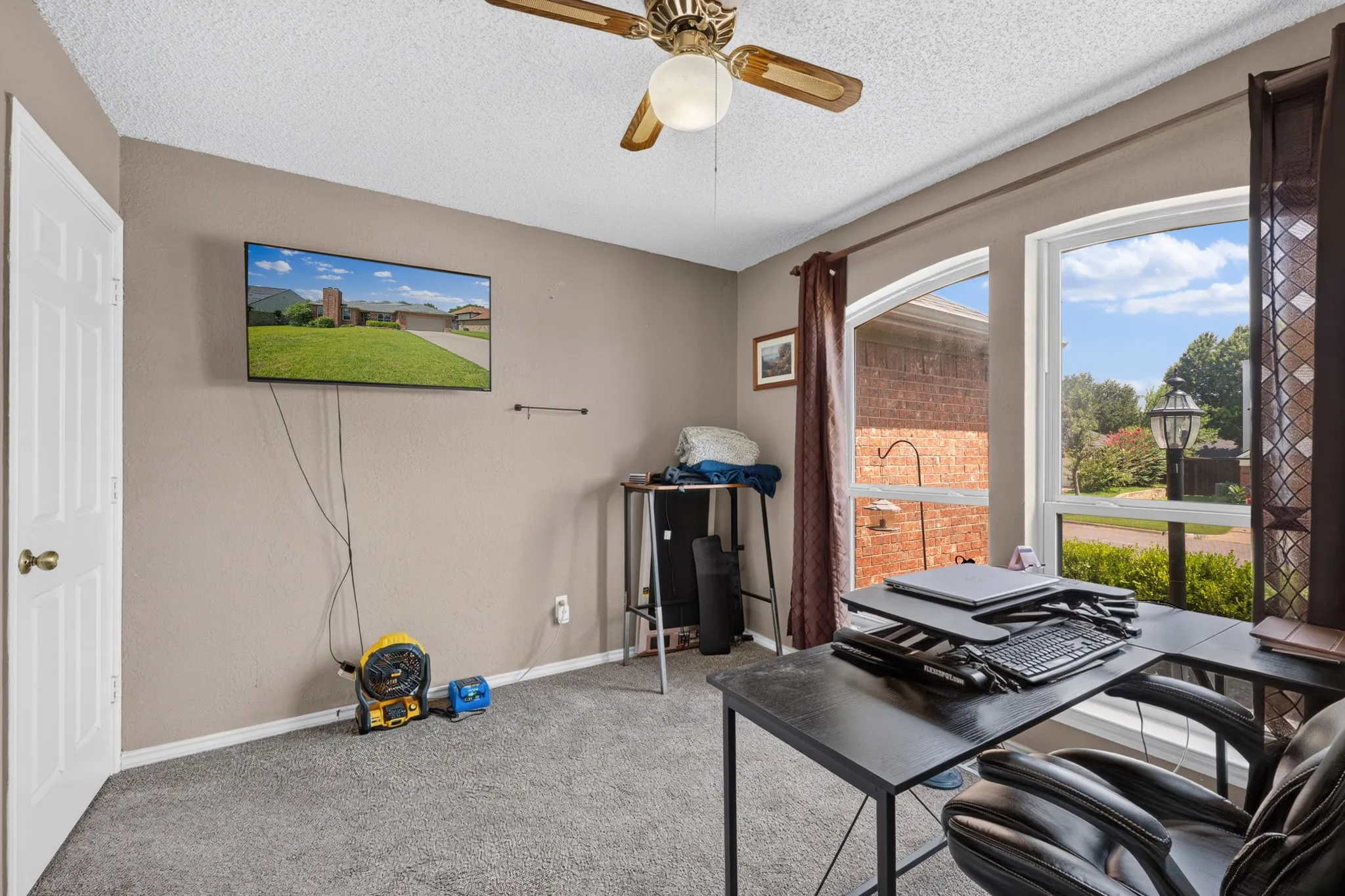 Room featuring arched windows, carpeted flooring, a ceiling fan with integrated lighting, and painted walls