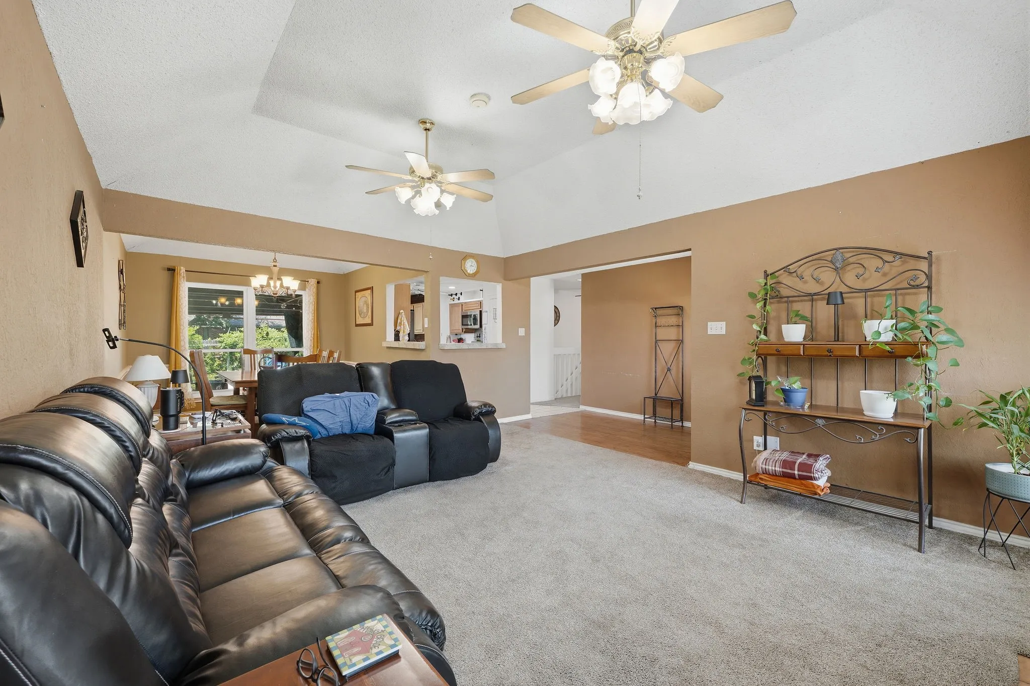 Spacious living area featuring vaulted ceilings, ceiling fans, and neutral-toned wall paint