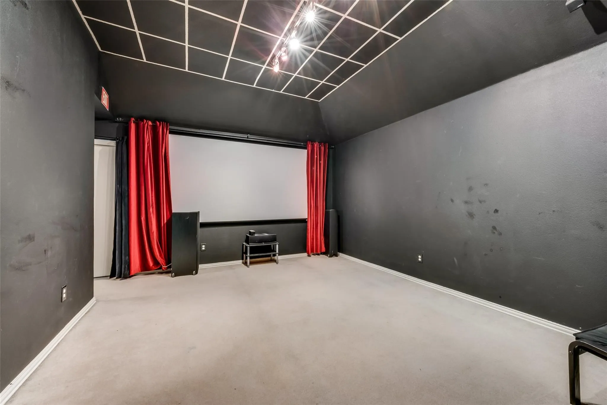 Dedicated media room featuring a large projection screen and dark wall finishes