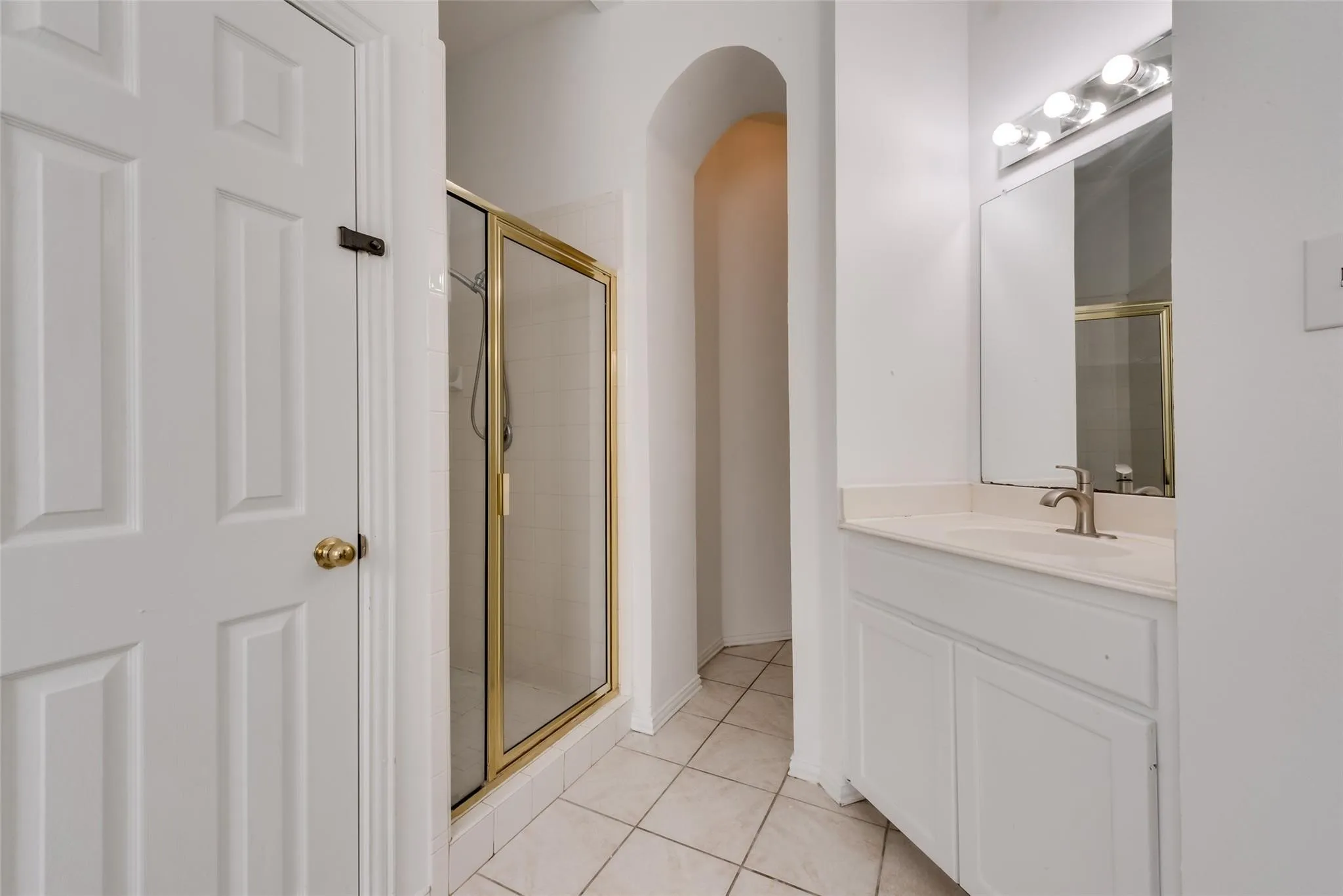 Bathroom featuring a white vanity with an integrated sink, a frameless mirror, and a three-light vanity bar