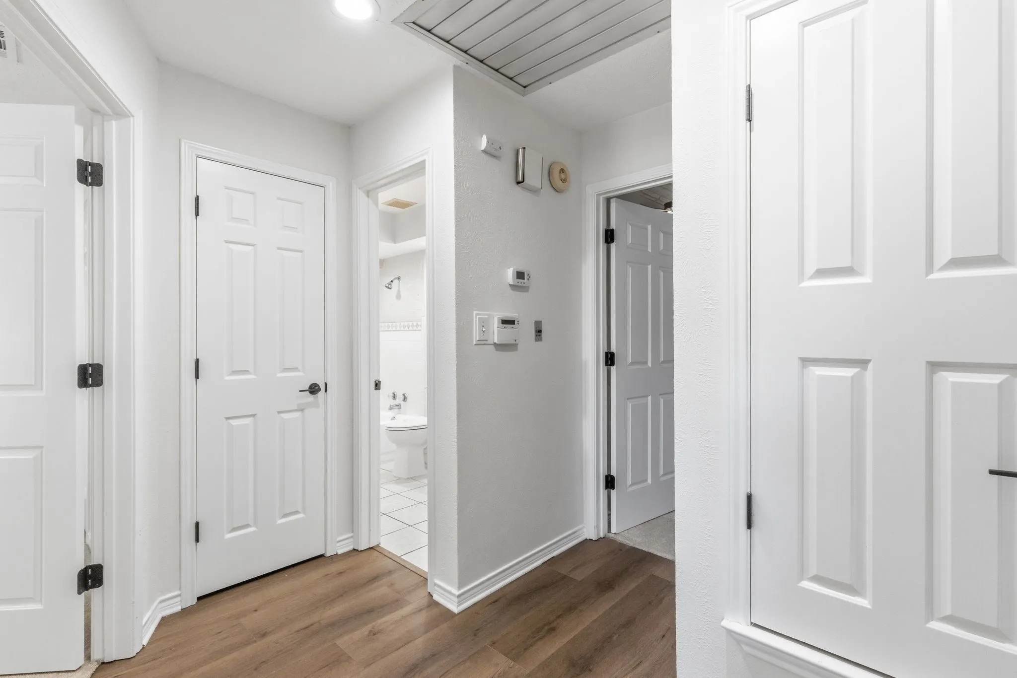 Hallway featuring wood-finish flooring, recessed lighting, white paneled doors, and white baseboards