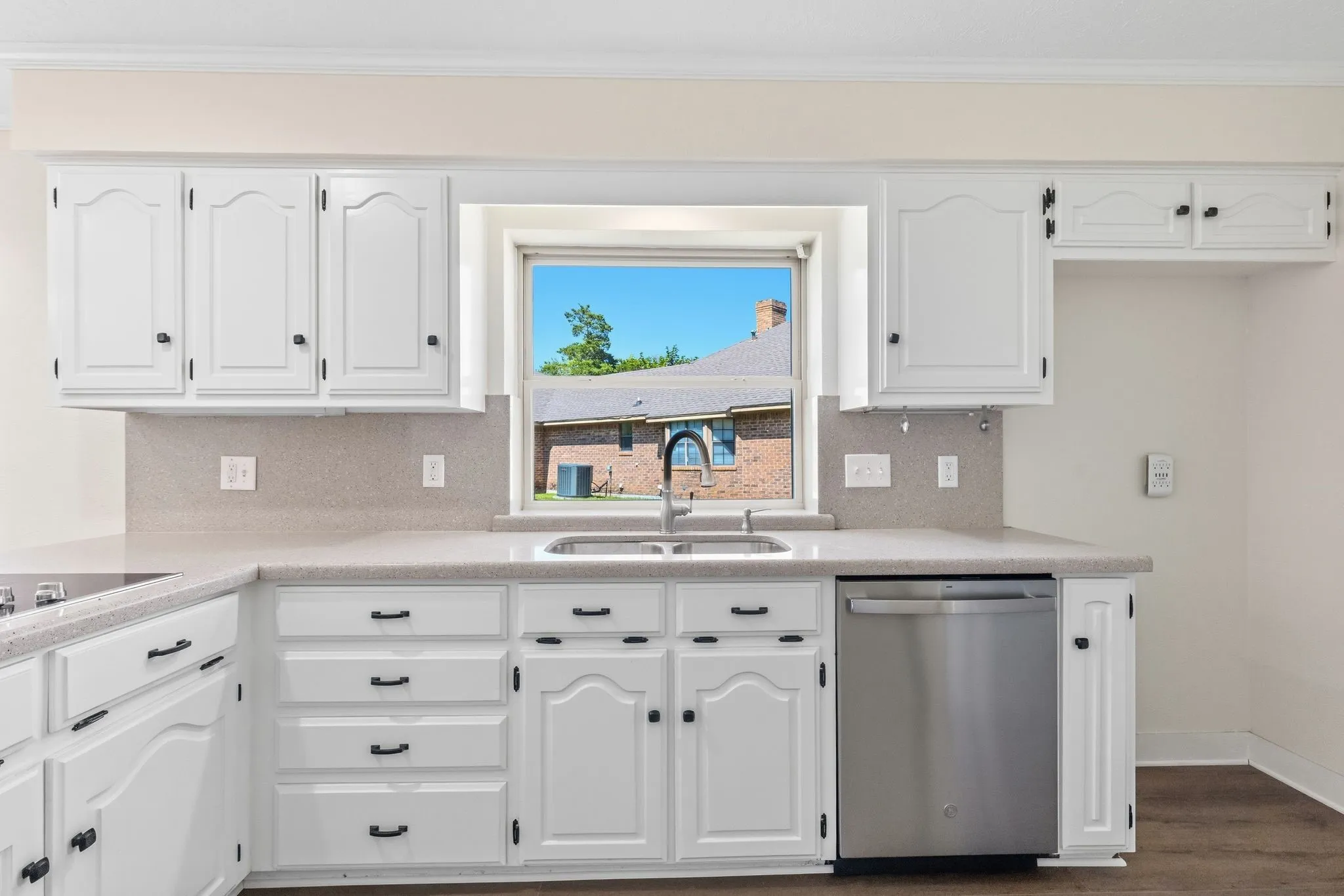 Kitchen featuring white cabinetry, light-colored countertops, a double-basin sink with a black gooseneck faucet, a stainless steel dishwasher, and wood-finish flooring