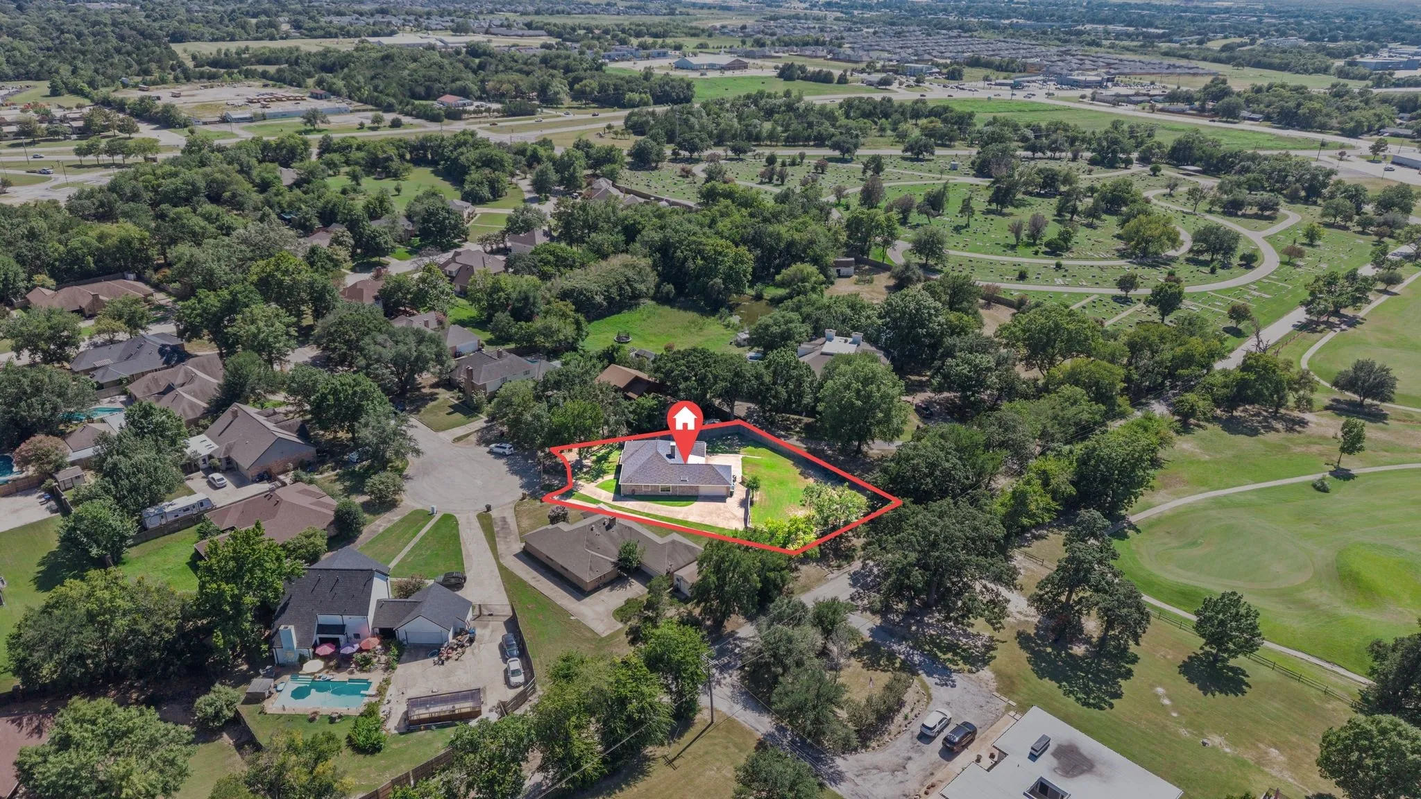 Aerial view showcasing a residential property bordered by mature trees and a manicured green space