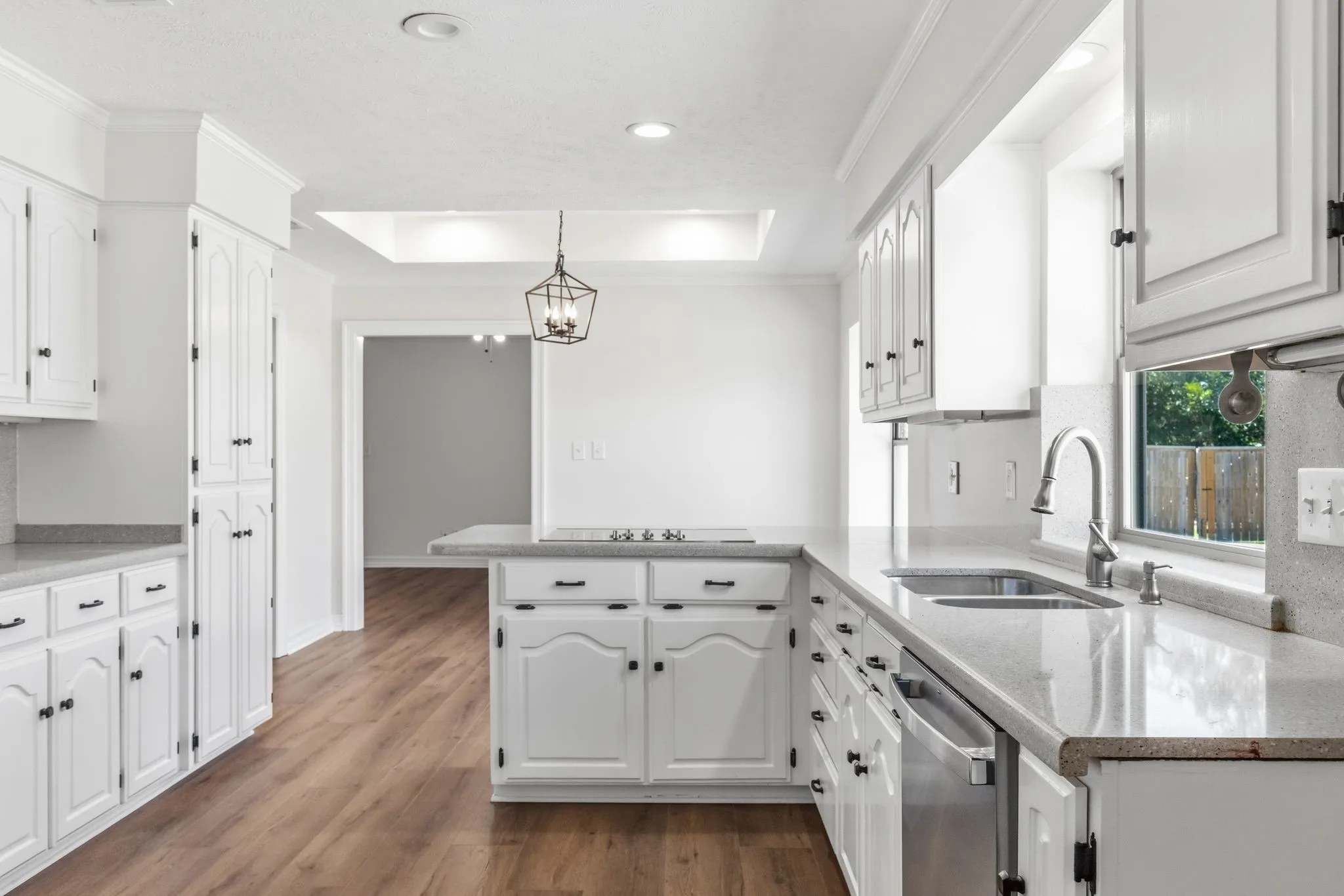 Kitchen featuring white cabinetry, light-toned countertops, wood-finish flooring, recessed lighting, and a stainless steel sink with a gooseneck faucet