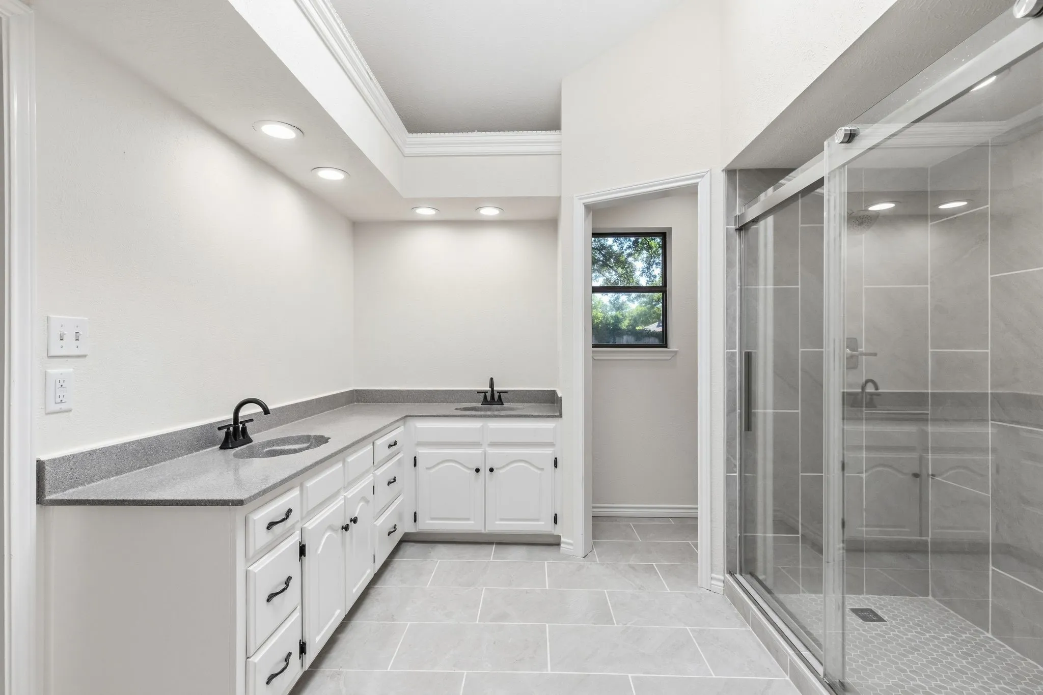 Dual vanity with gray countertops, white cabinetry, and matte black fixtures