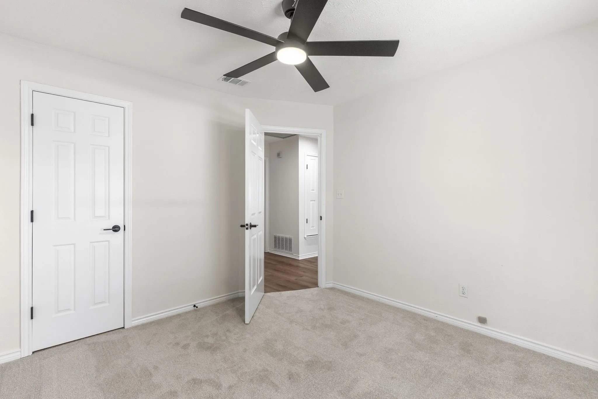 Carpeted room featuring a ceiling fan with integrated lighting, white walls, and white trim