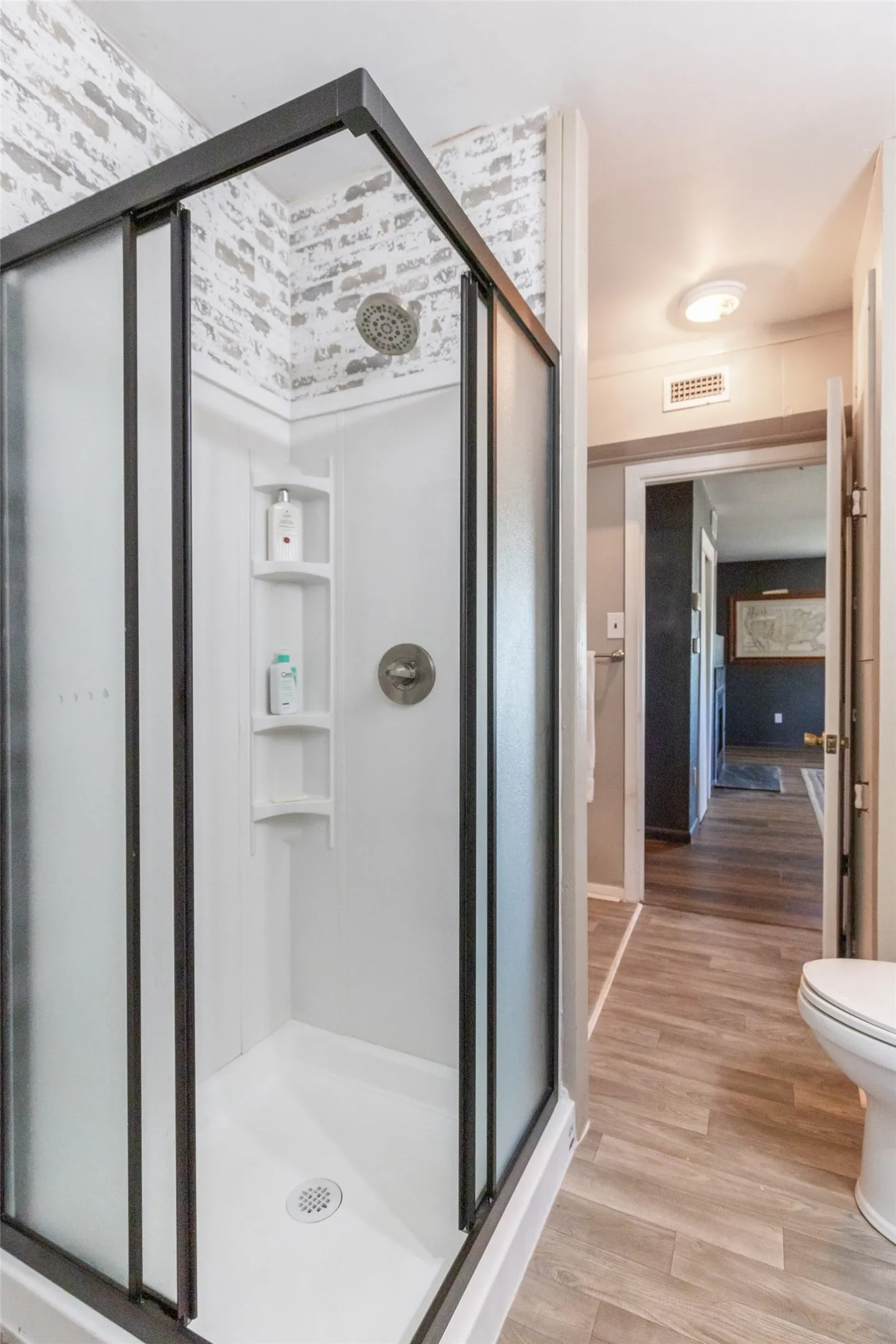 Shower enclosure with dark-framed frosted glass doors, a white shower pan, and white subway tile-look surround
