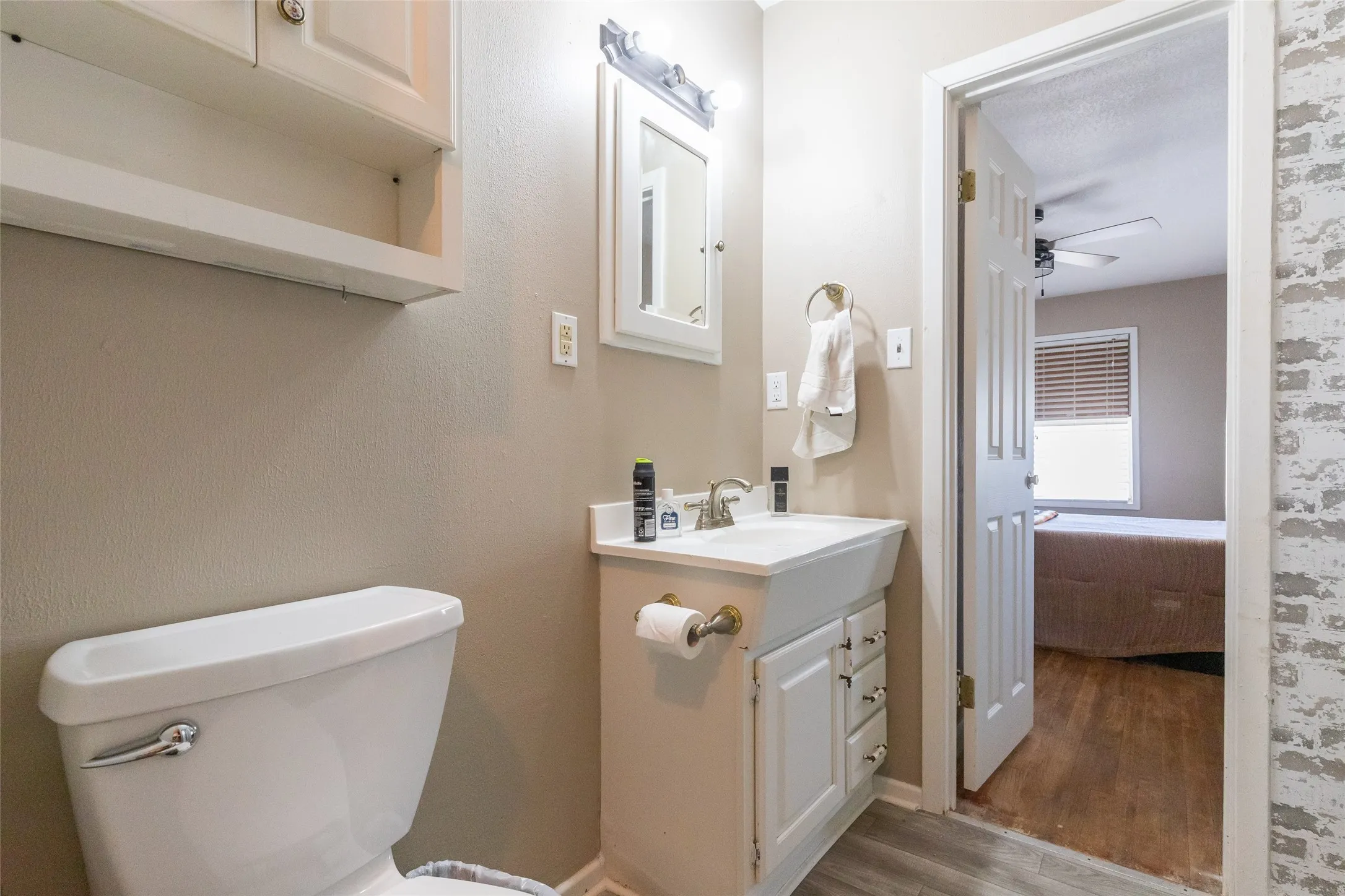 Bathroom featuring a vanity with integrated sink, white cabinetry, and wood-finish flooring