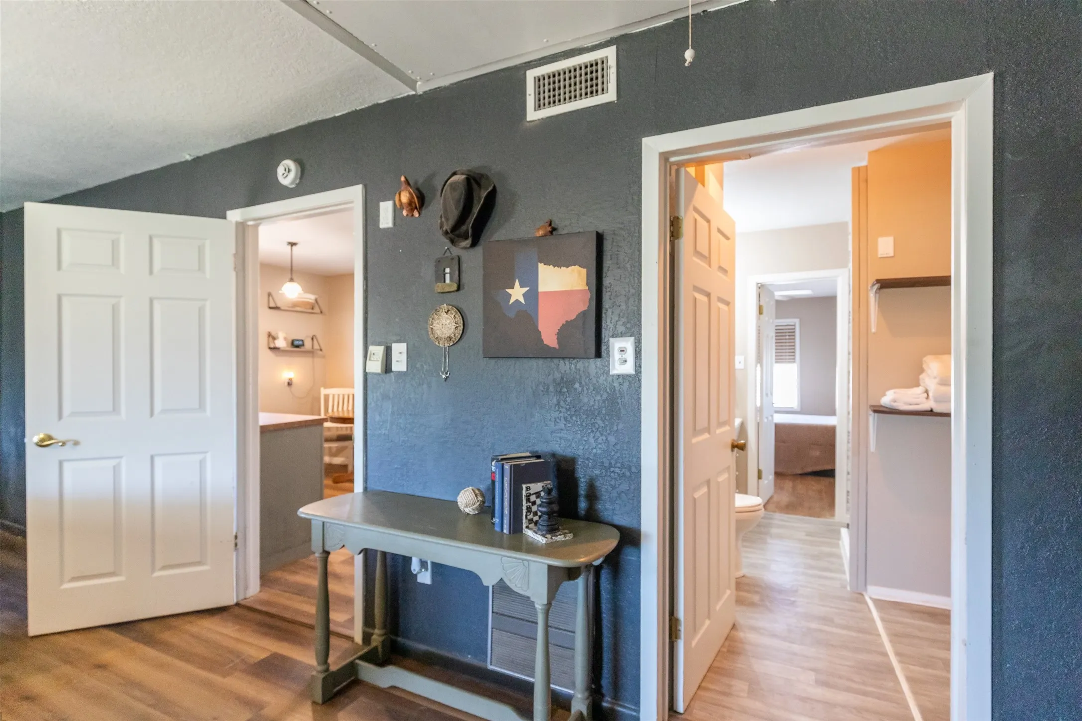 Hallway with wood-finish flooring and textured dark gray walls