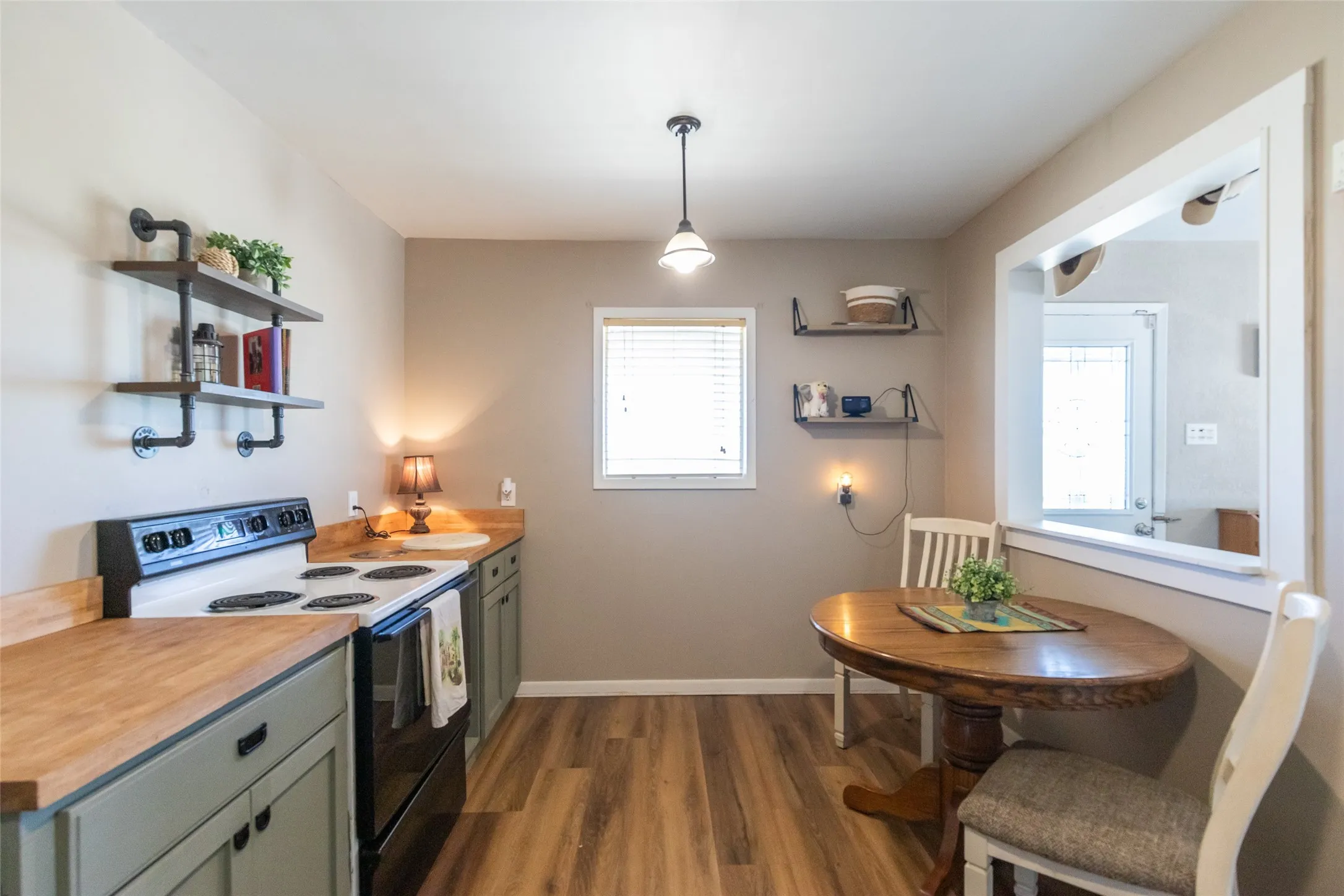Kitchen featuring wood-finish flooring, light green cabinetry, and wood countertops
