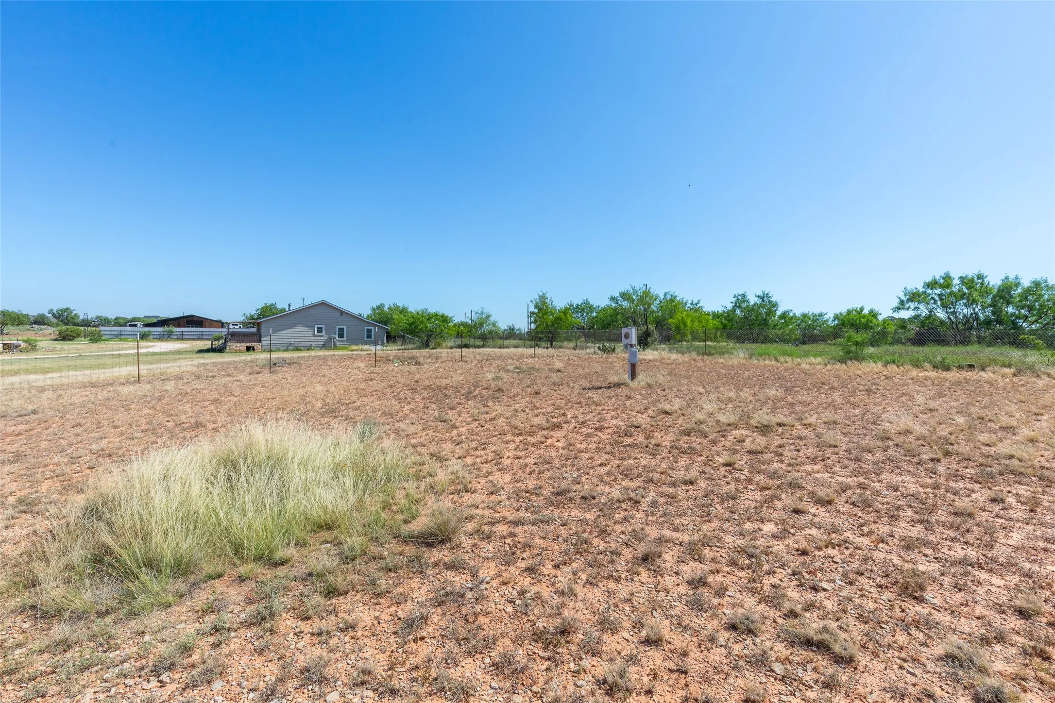 Expansive open terrain featuring natural vegetation and a distant single-story structure