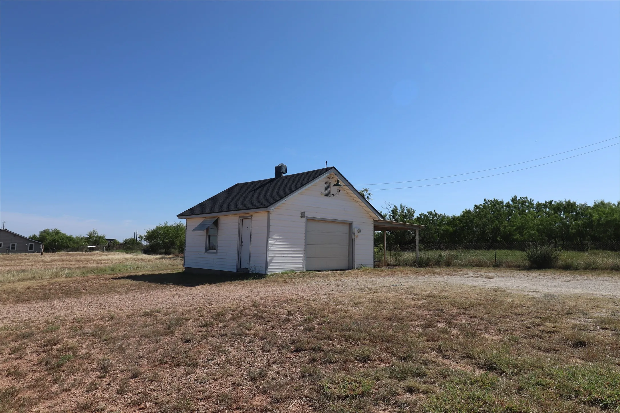 Detached structure with white siding and a dark shingle roof