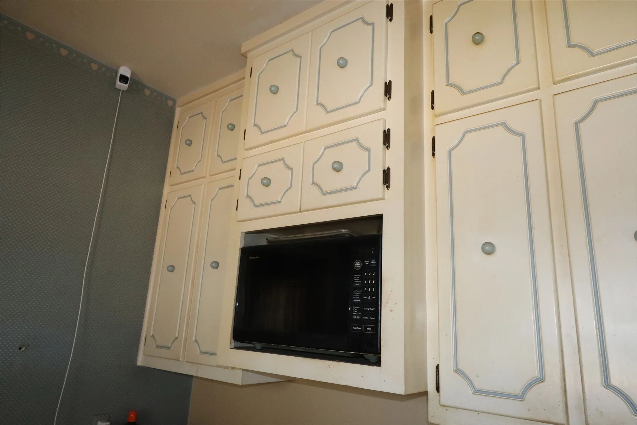 Upper cabinetry with decorative paneling and rounded knobs, featuring an integrated microwave oven