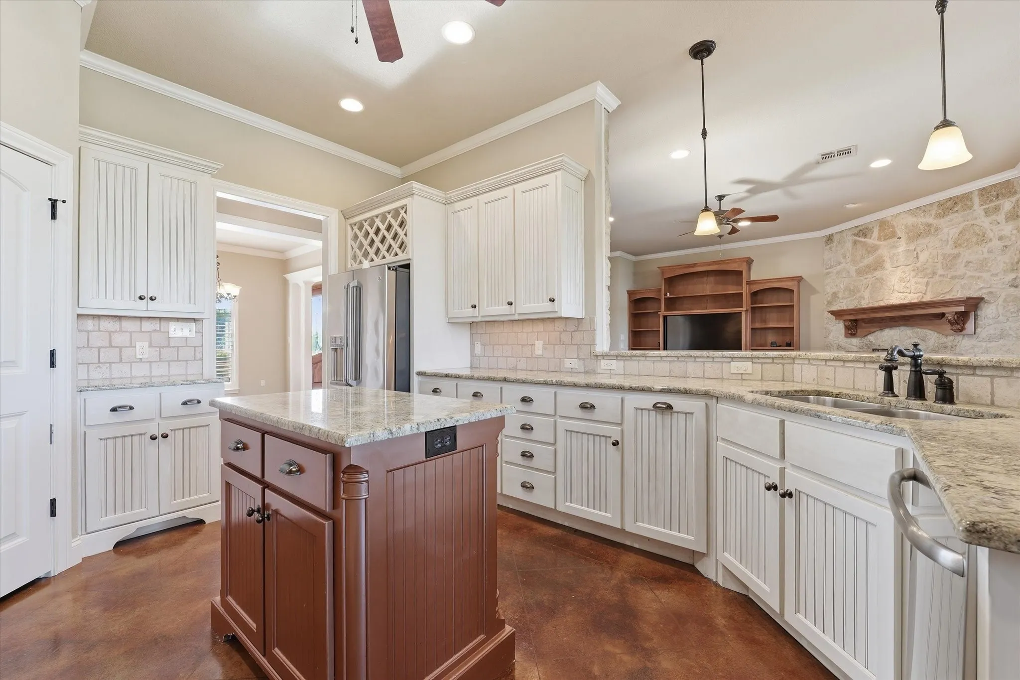 Kitchen featuring white beadboard cabinetry, granite countertops, and a central island with wood-finish paneling