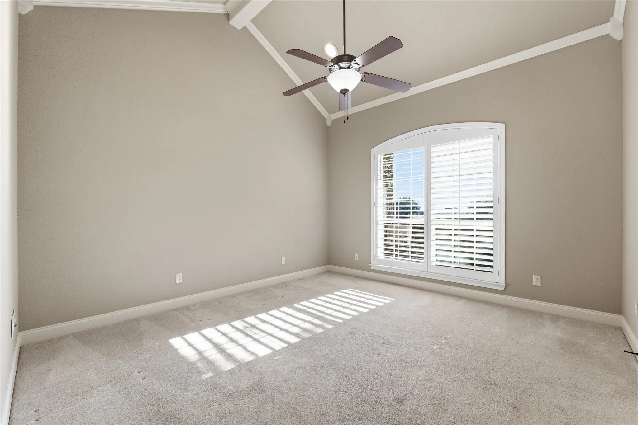Room featuring a high vaulted ceiling with exposed beams, light-toned wall paint, and white crown molding