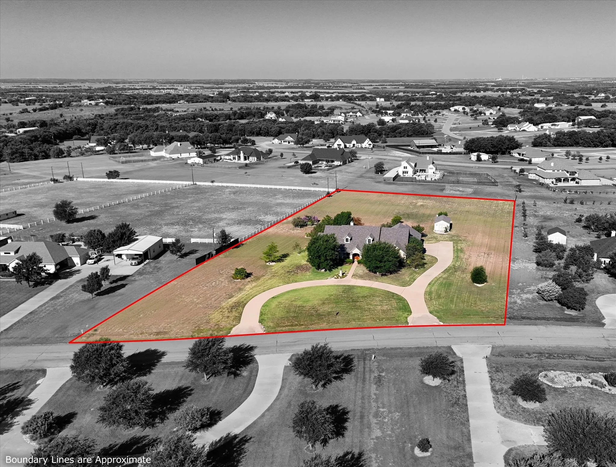 Expansive property featuring a circular driveway, mature trees, a detached outbuilding, and significant undeveloped land