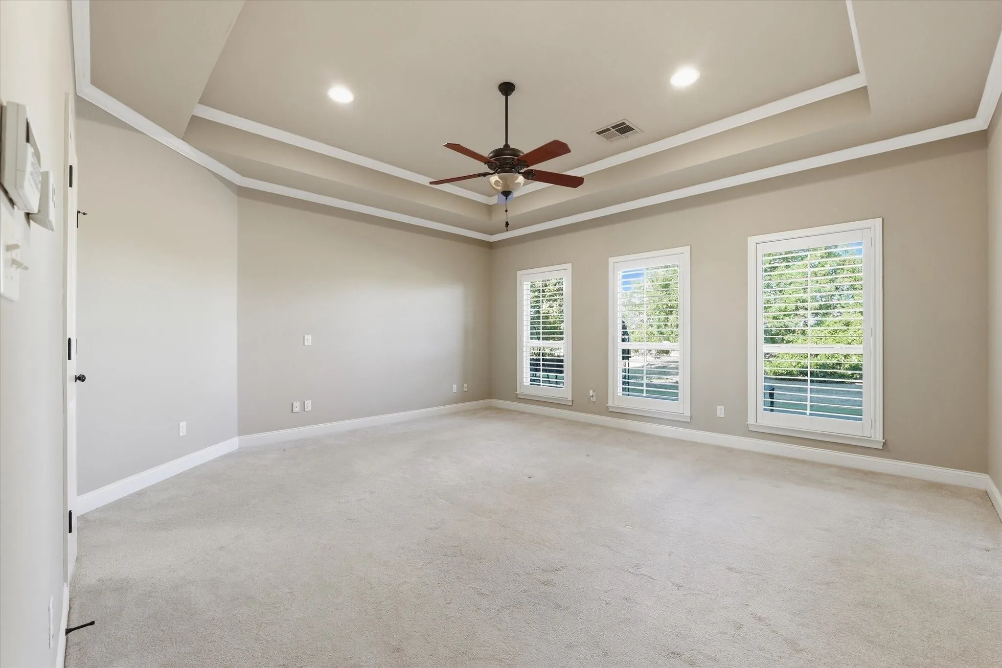 Spacious room with tray ceiling, recessed lighting, and a ceiling fan