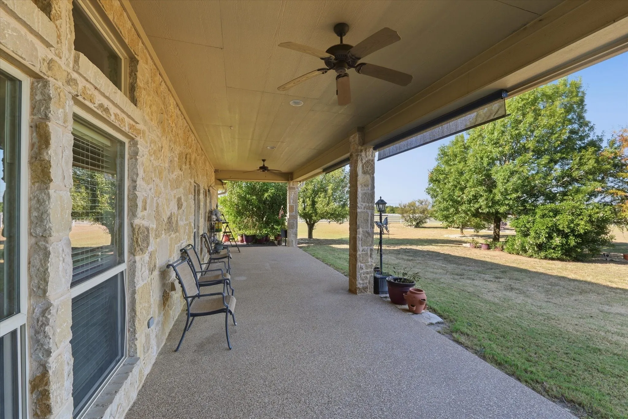 Spacious covered patio with exposed aggregate flooring and multiple ceiling fans