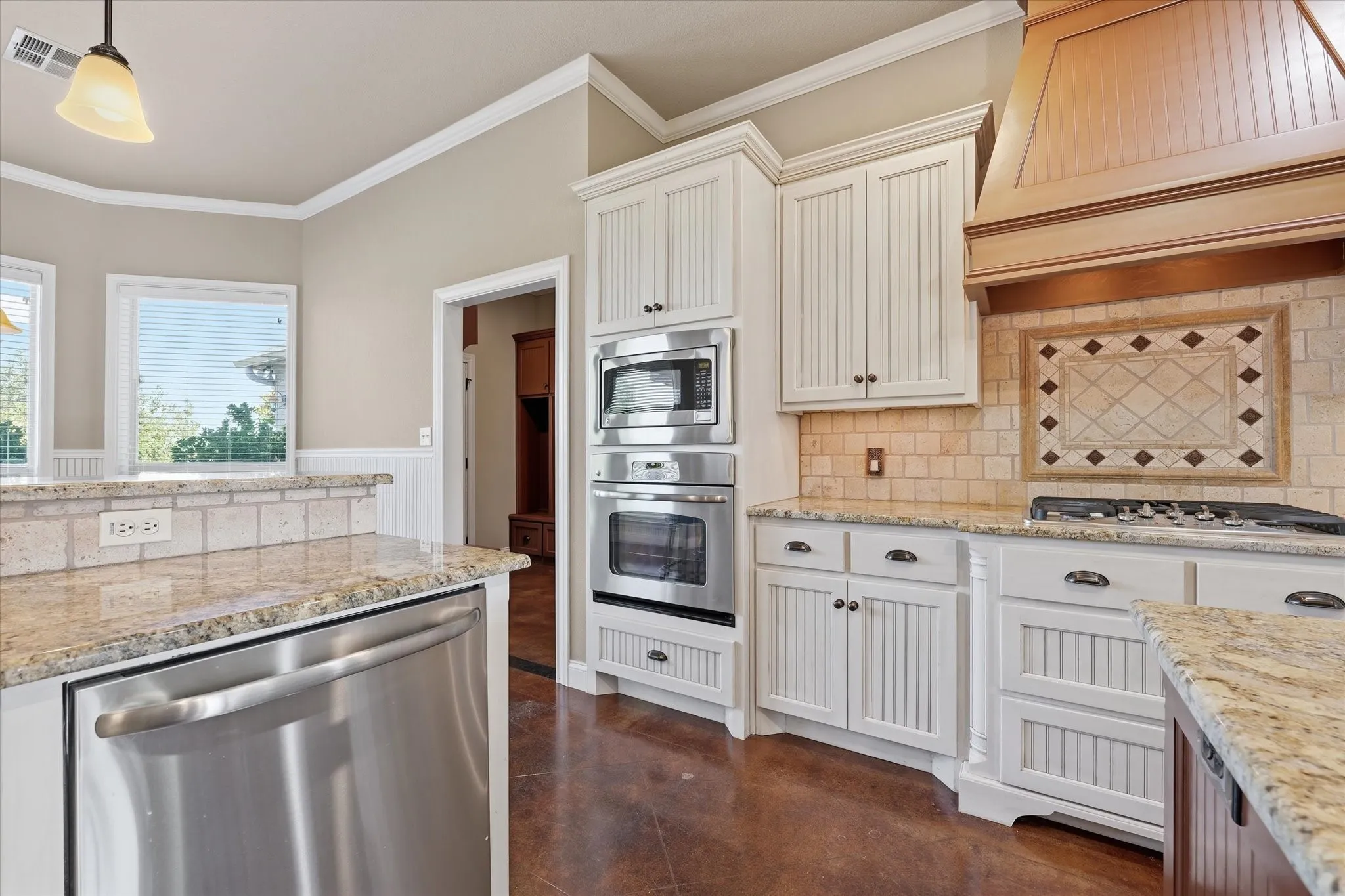 Kitchen featuring white beadboard cabinetry, granite countertops, stainless steel appliances, a built-in oven and microwave, and a decorative tile backsplash