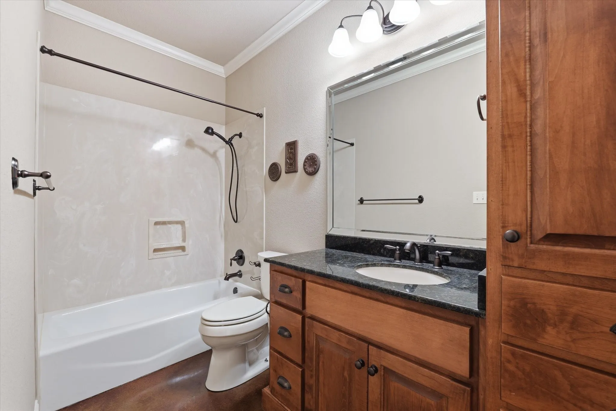 Bathroom featuring a full vanity with dark countertop, undermount sink, and wood-finish cabinetry