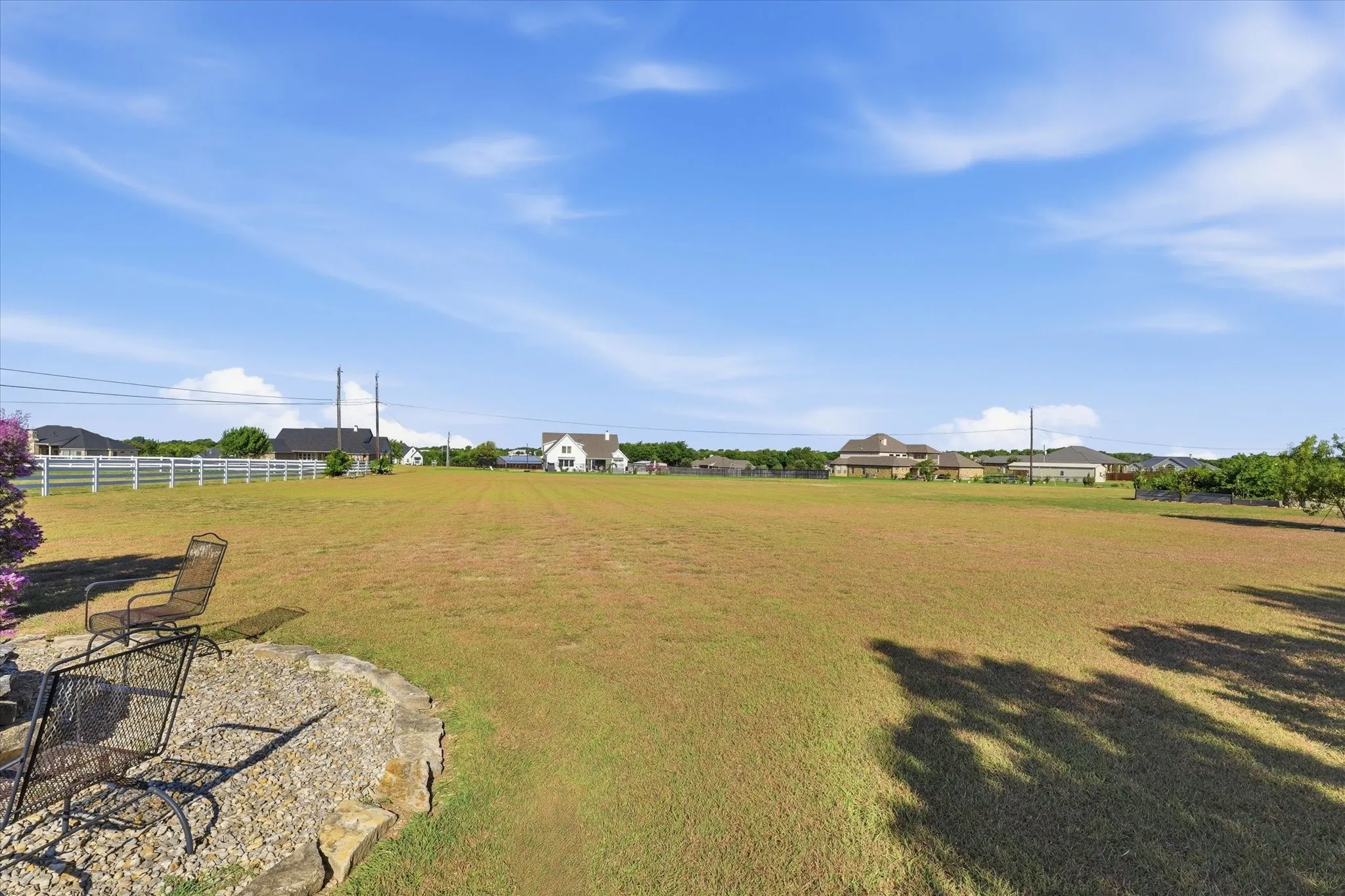 Expansive grassy lot with a gravel patio area and a stone border