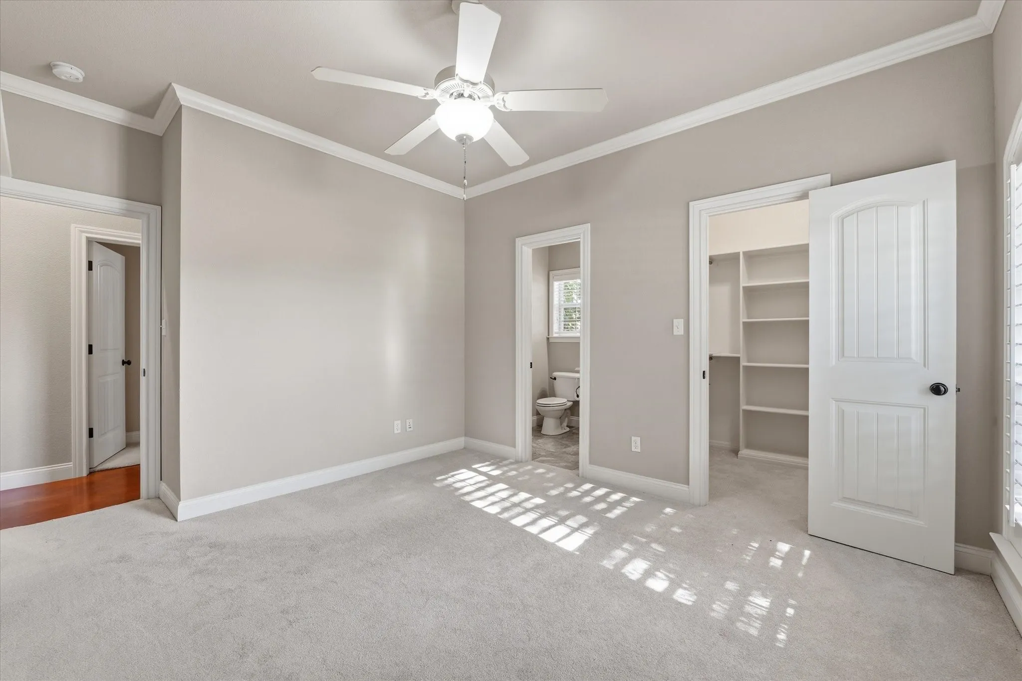 Neutral-toned room featuring light carpet flooring and crown molding