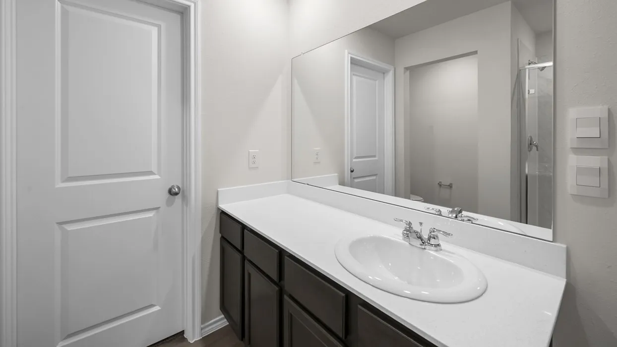 Bathroom vanity featuring a white countertop, an undermount sink with chrome fixtures, a dark wood-finish cabinet, and a large wall-mounted mirror