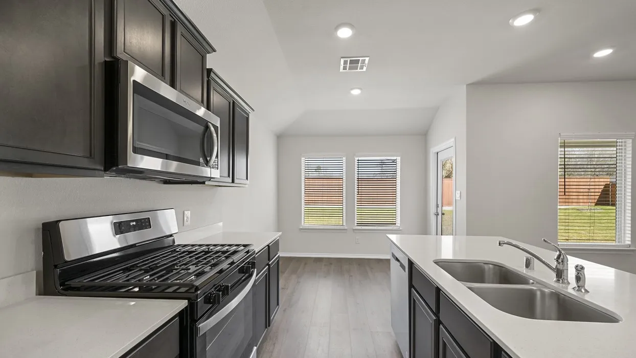 Kitchen featuring stainless steel appliances, dark wood-finish cabinetry, light countertops, and recessed lighting