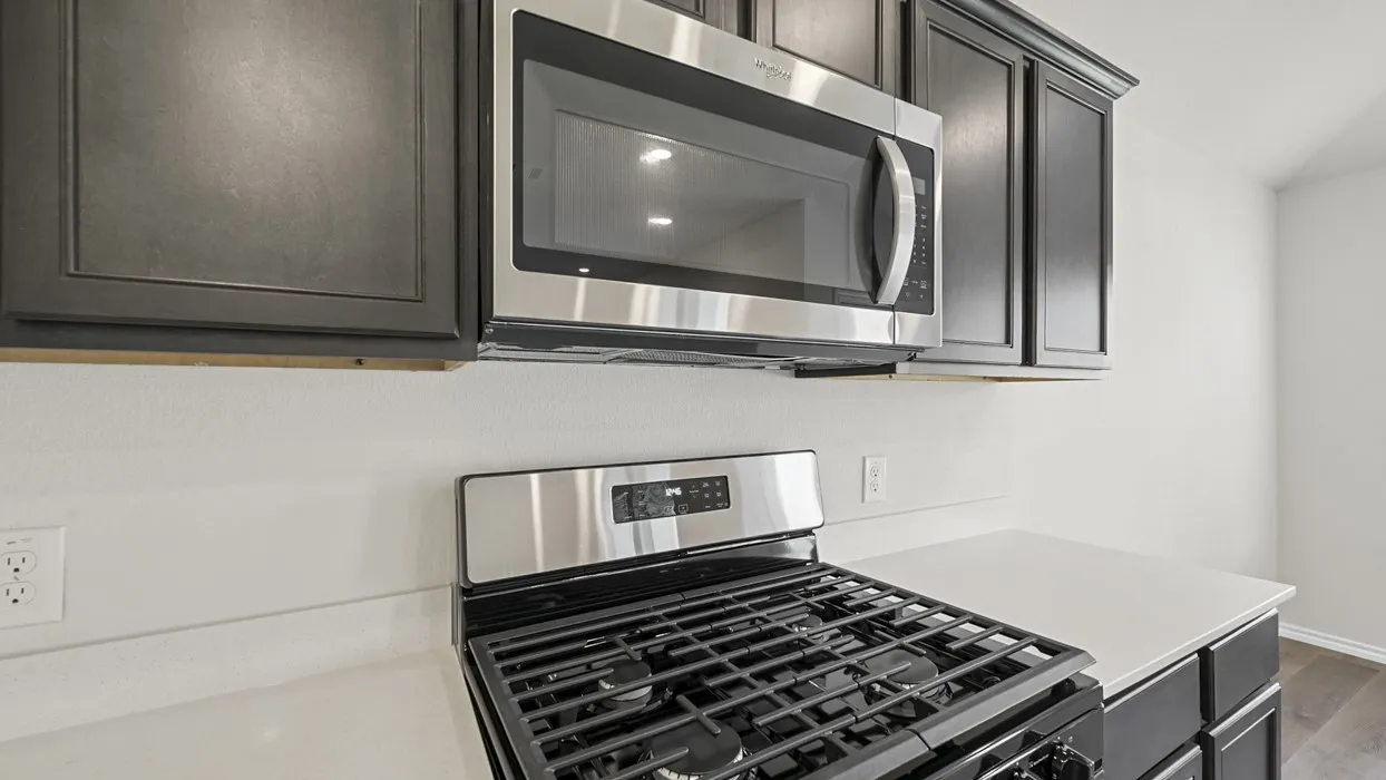 Stainless steel microwave and gas range set against dark cabinetry