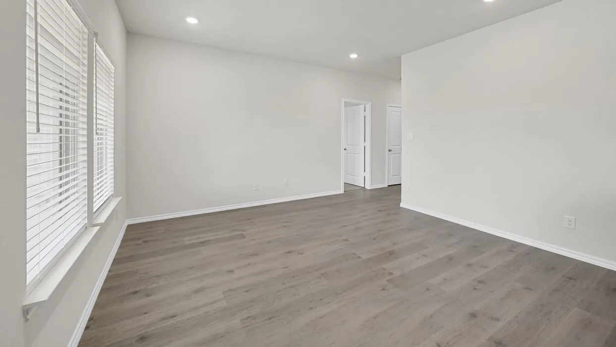 Spacious room featuring wood-finish flooring, recessed lighting, and white baseboards