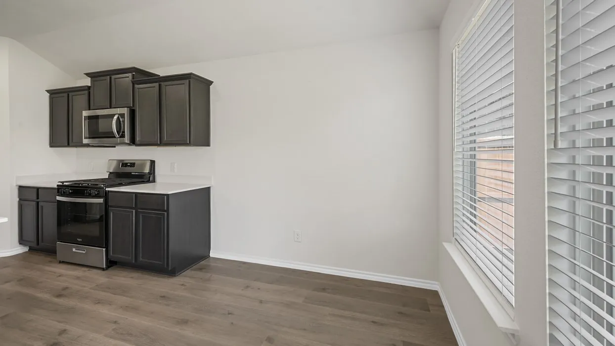 Kitchen area featuring dark cabinetry, stainless steel appliances, white subway tile backsplash, and wood-finish flooring