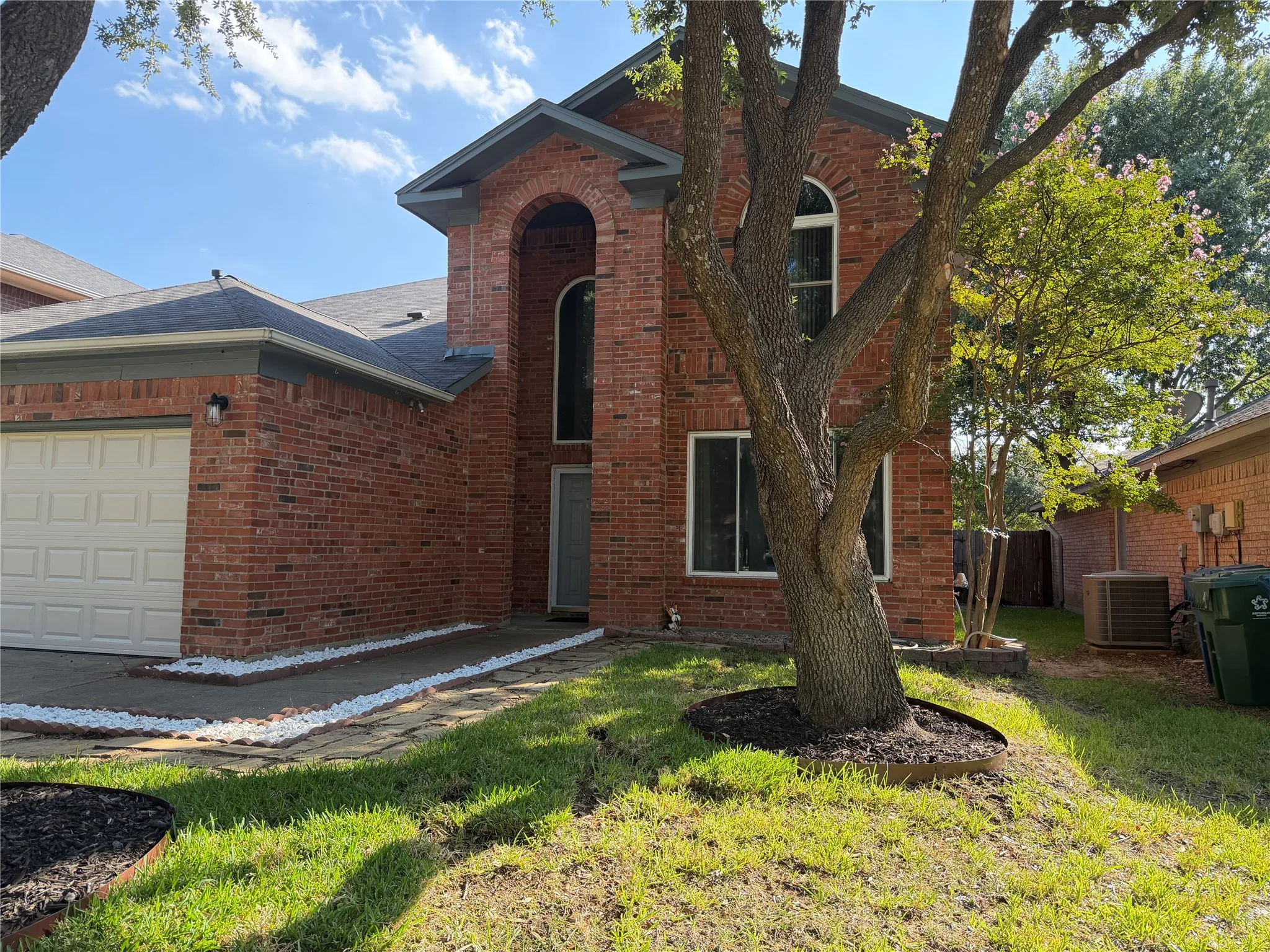 Brick exterior with an arched entryway and an attached garage