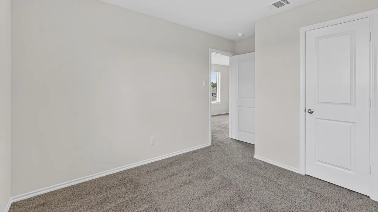 Carpeted interior room with light gray walls, white trim, and a white paneled door with a silver knob